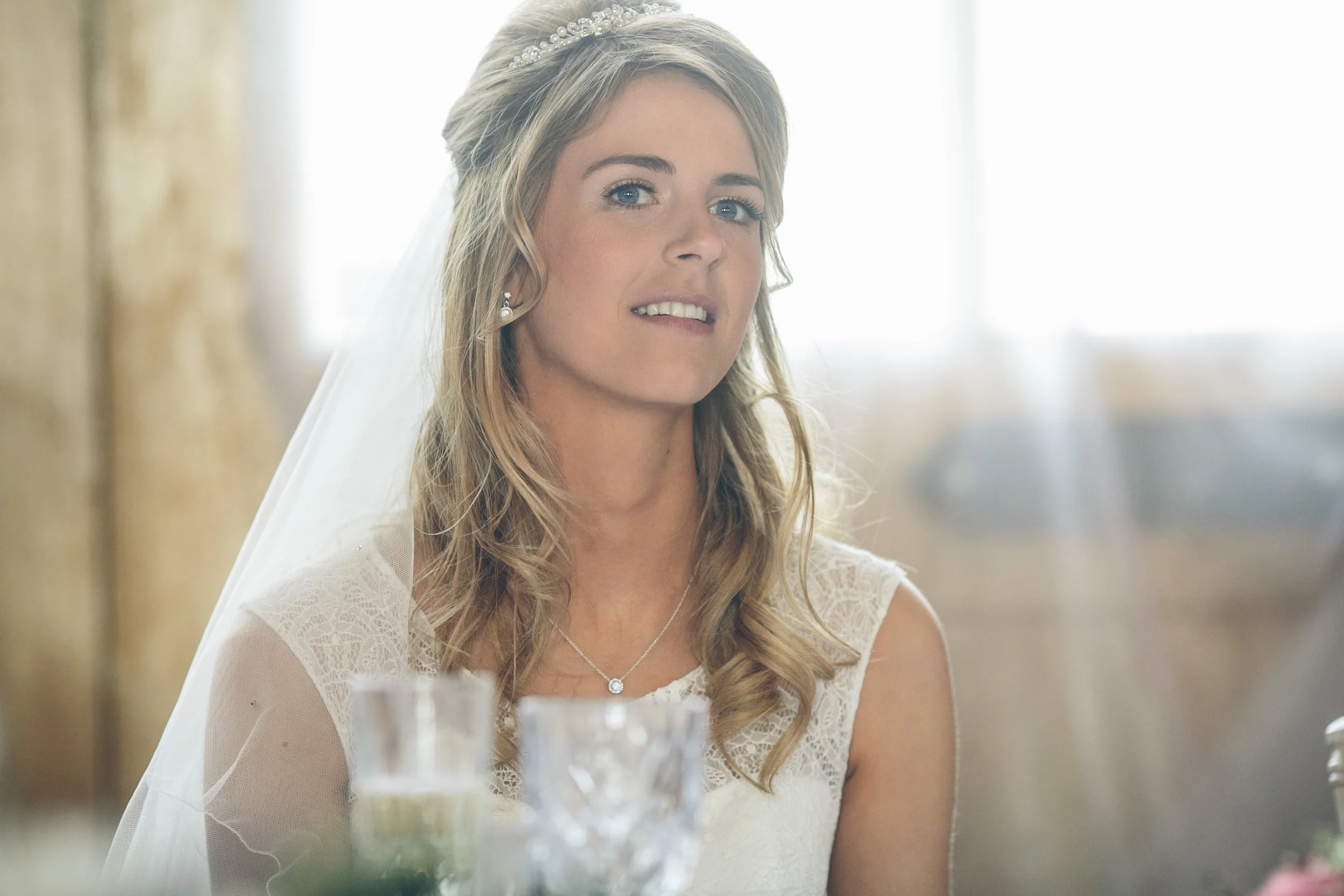 A woman in a wedding dress, wearing a veil and jewelry, appears emotional, possibly during a wedding ceremony.