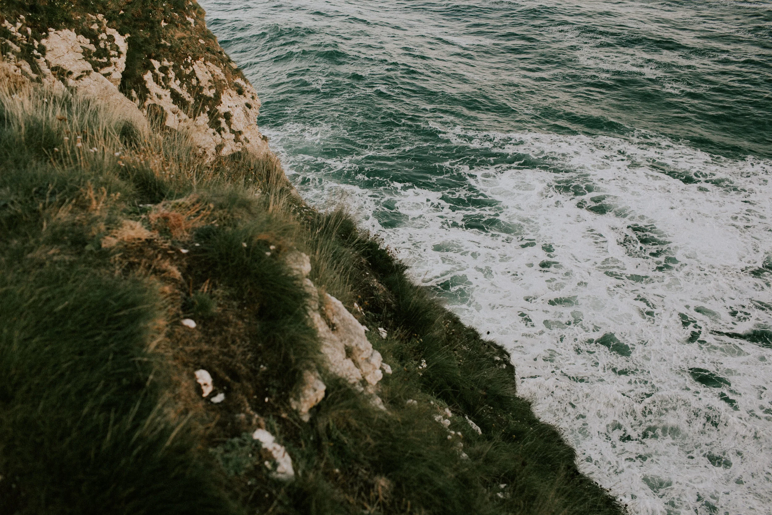Cliffside overlooking the ocean with waves crashing against the rocks below.