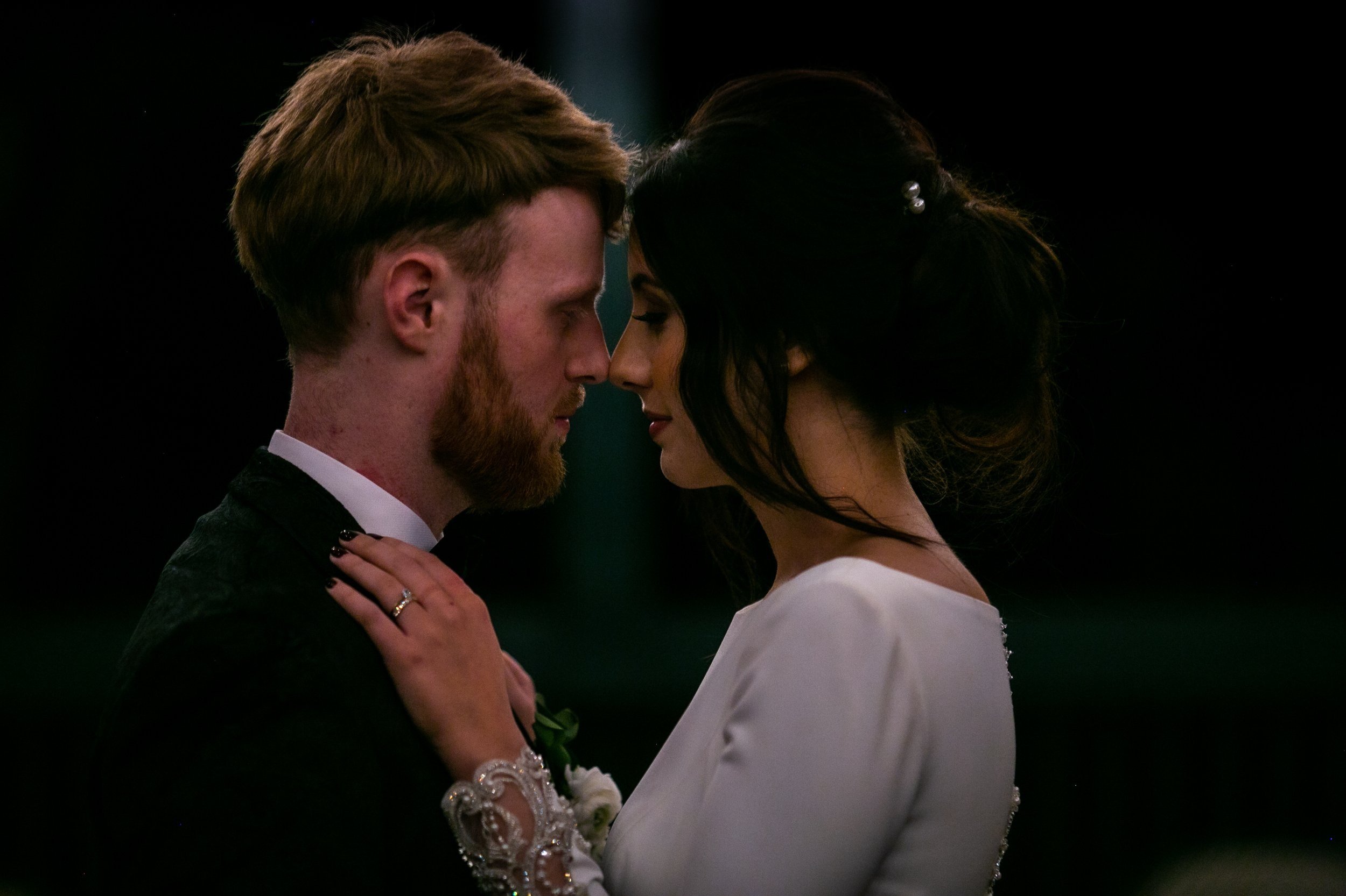 A bride and groom share an intimate moment, with their foreheads touching and eyes closed, during their wedding.