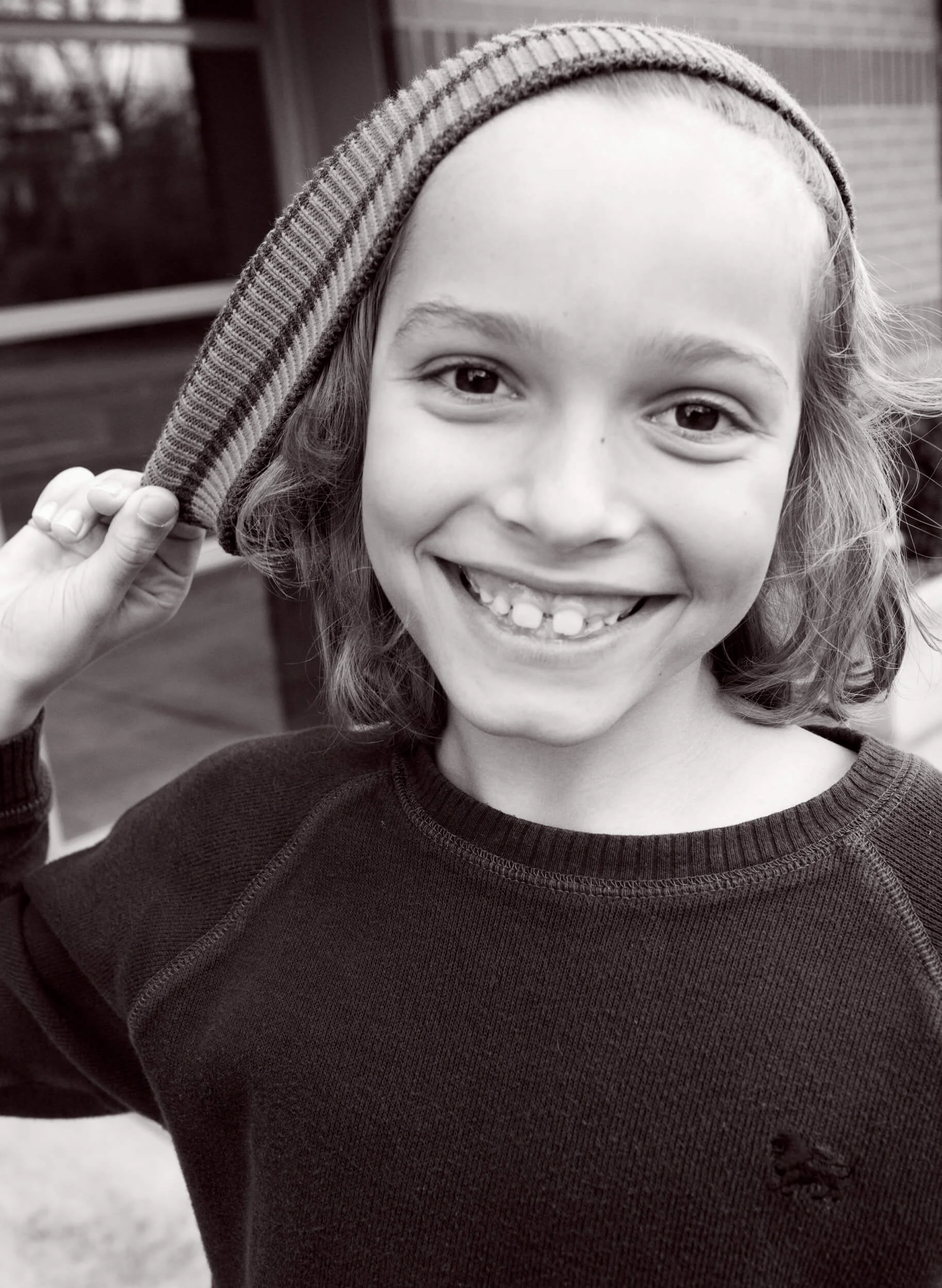 Boy-pulling-hat-with-a-huge-big-smile-Black-and-white-Photography