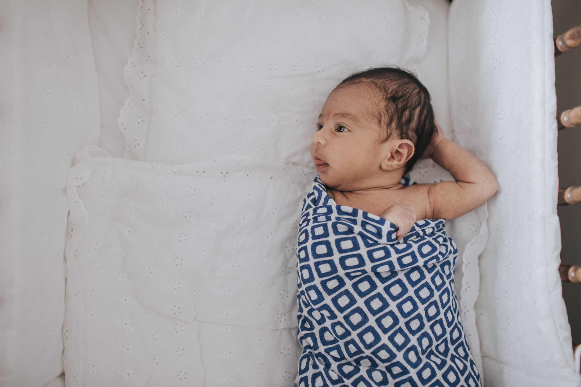 newborn baby laying wrapped in a blue swaddle blanket