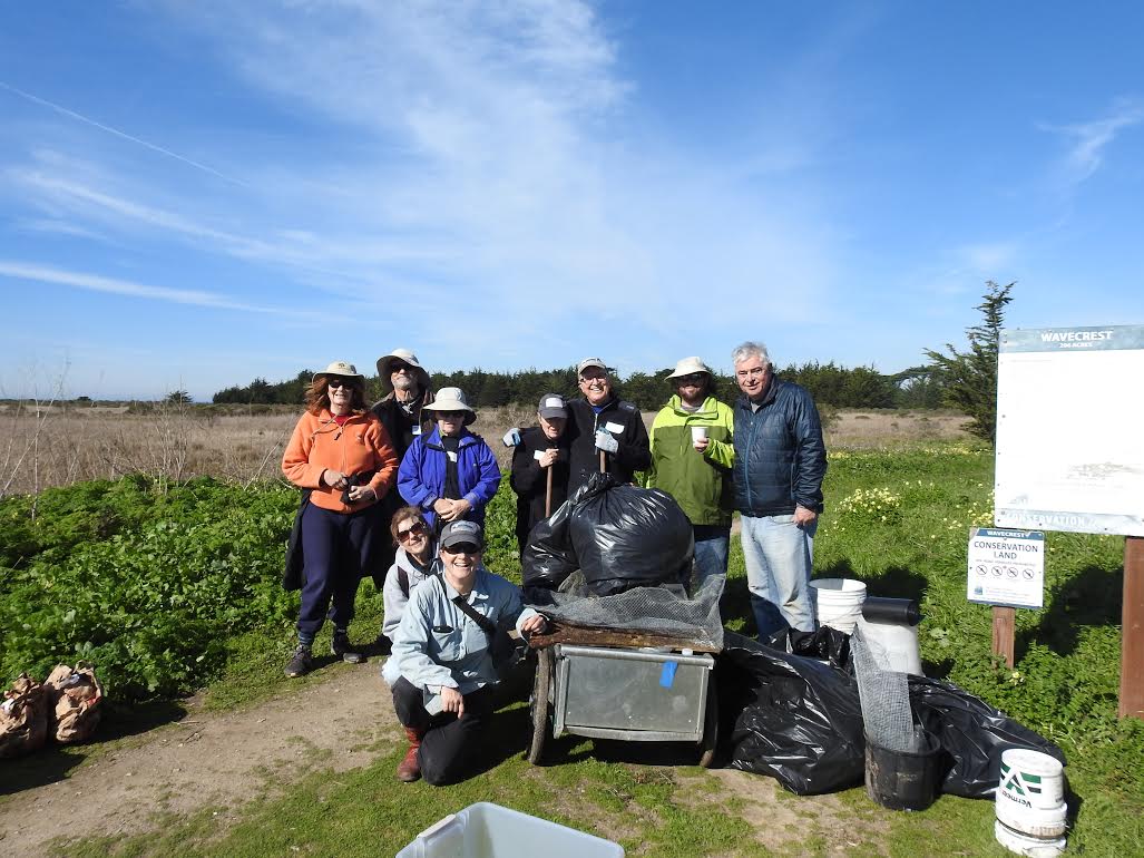 Volunteers celebrating a successful workday with the pile of trash pulled from the Wavecrest property.