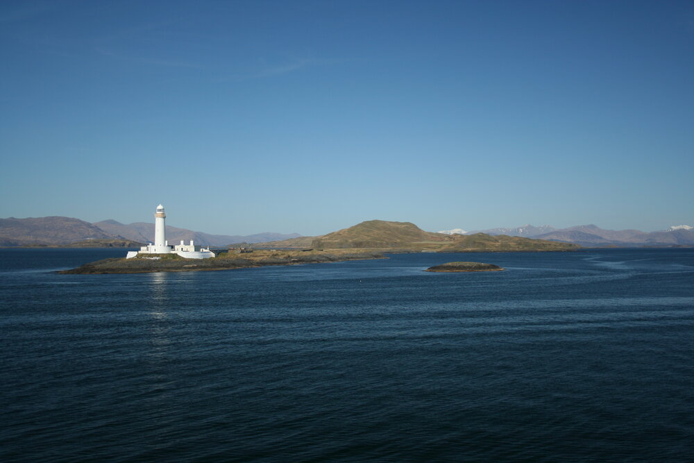 Lighthouse with snowcapped Highland peaks in the distance