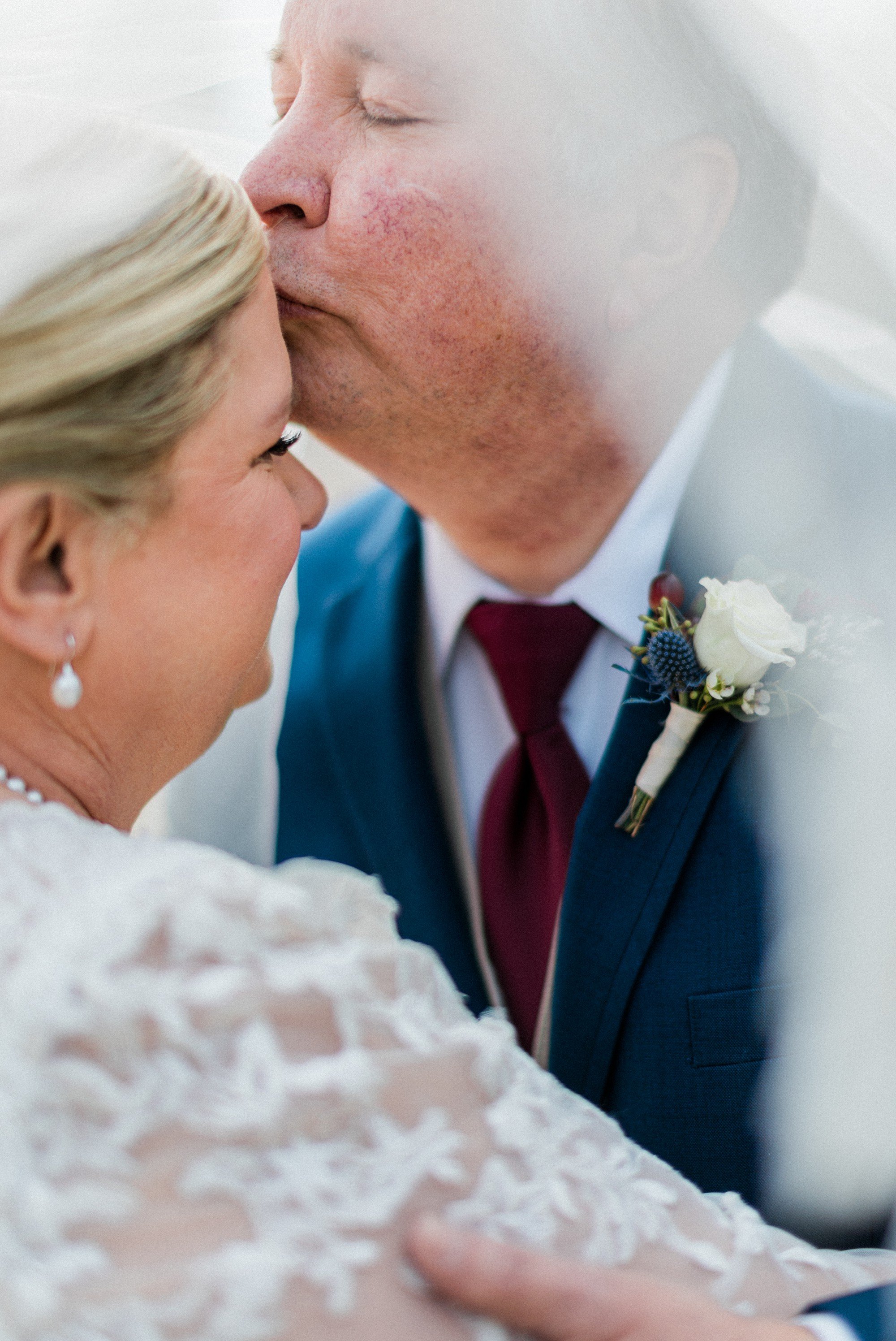 groom kissing bride on the forehead