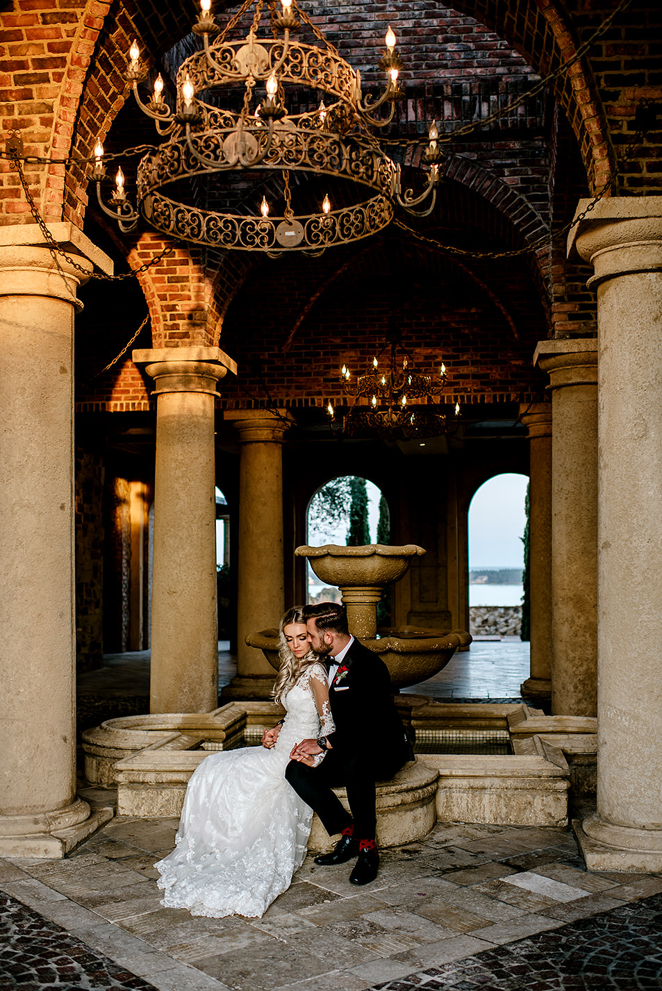 Portrait of bride and groom sitting by a water fountain at Bella Collina Florida, during sunset.