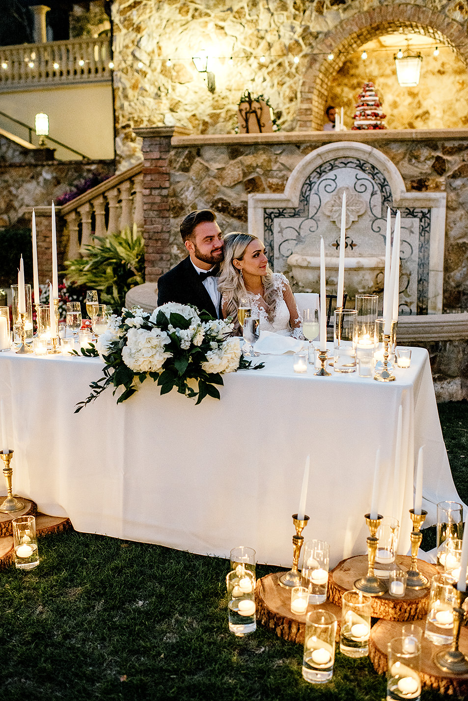 Bride and groom sitting at their candle filled sweetheart table during their reception at Bella Collina Florida
