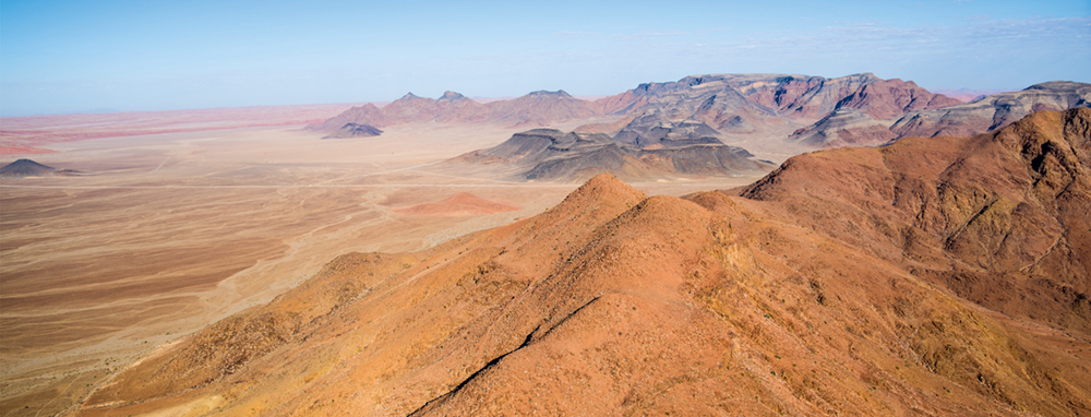 Wenn man sich Sossusvlei nähert, verwandelt sich die steinige Landschaft des Naukluft Gebirges in das sandige Meer des NamibRand Naturparks in den Farben Gelb bis Rostrot Photo © 2016 Jürgen Wettke. All rights reserved