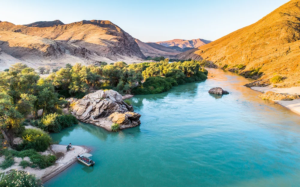 Seen from above, the Kunene looks almost like an oil painting; the beauty is unreal, with trees covering the green banks. The boat belongs to Serra Cafema Camp, the most beautiful lodge on the river Photo © 2018 Michael Poliza. All rights reserved. www.michaelpoliza.com