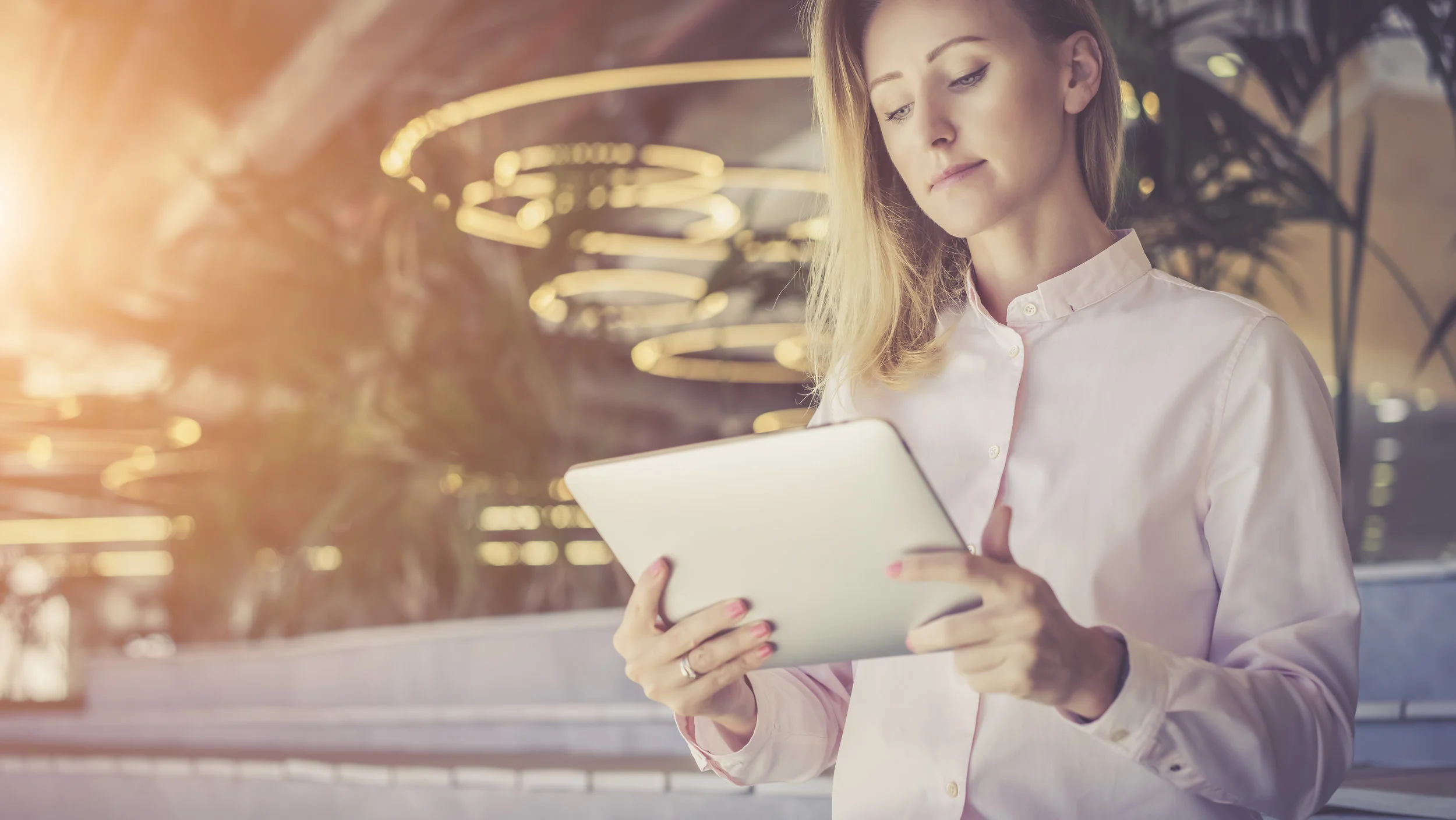A girl in a light pink shirt surf the Internet on a digital tablet.Business woman checks email on a tablet computer.Selective focus, film effect, blurred background.