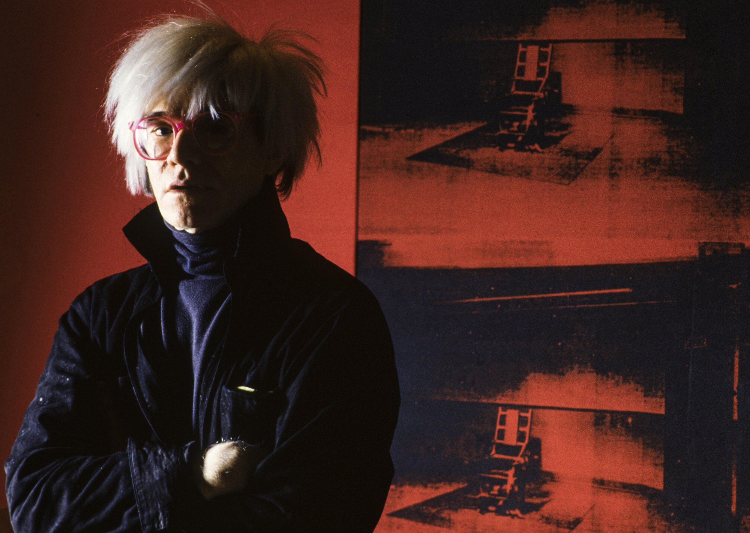 Andy Warhol, posiert vor dem Bild Little Electric Chair (1964/1965), Factory, Union Square West, New York, 1984 © Alberto Venzago