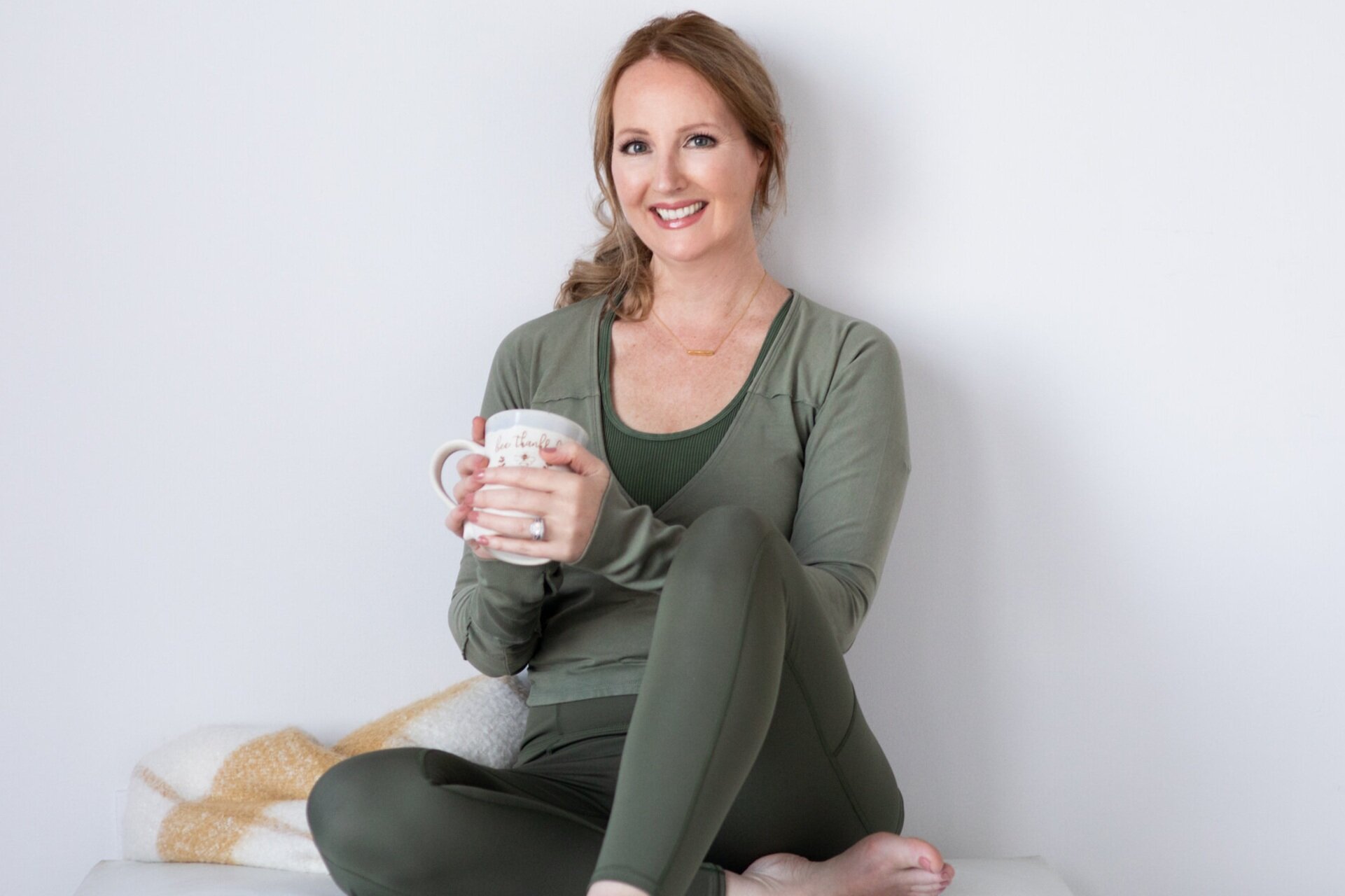 candid photo of Woman in green outfit sitting holding a coffee cup - highlighting the priority of fit + comfort during a photo session