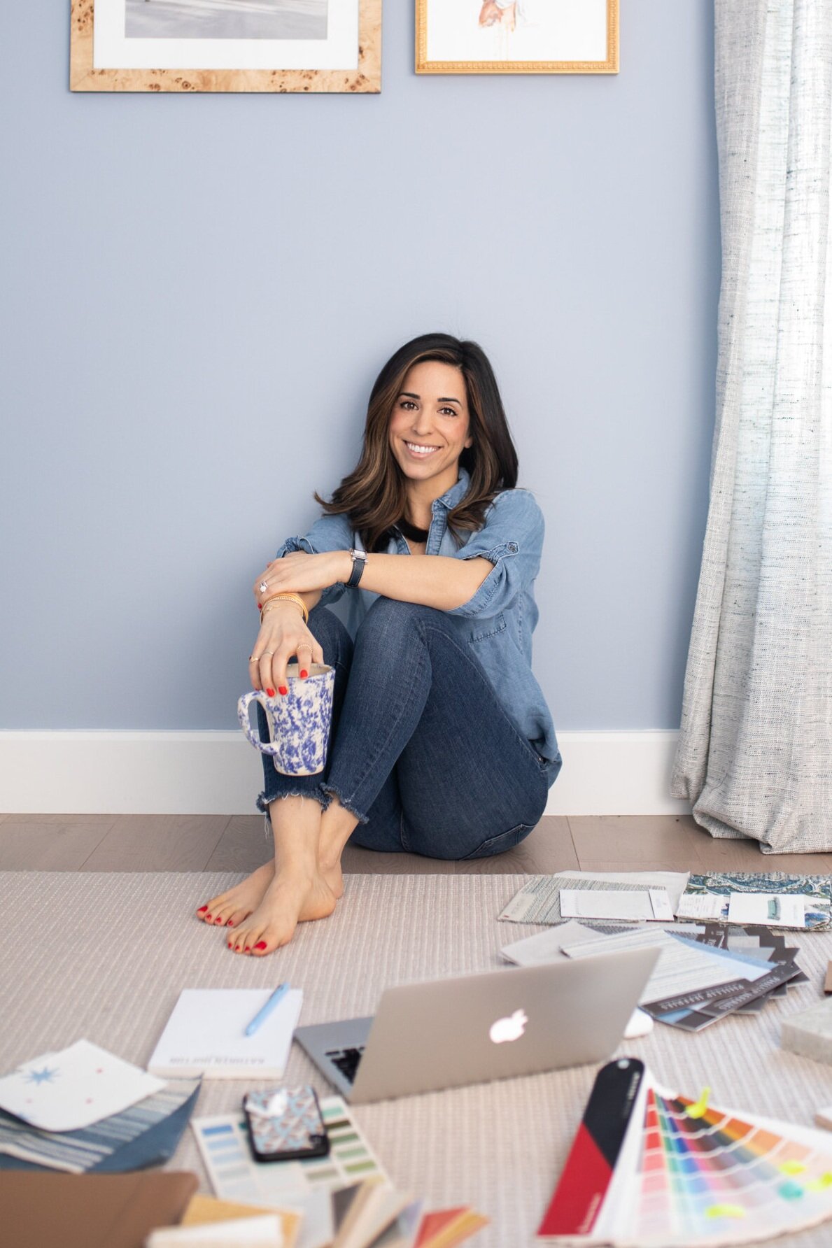 Woman sitting on floor holding cup with design samples during her personal branding session