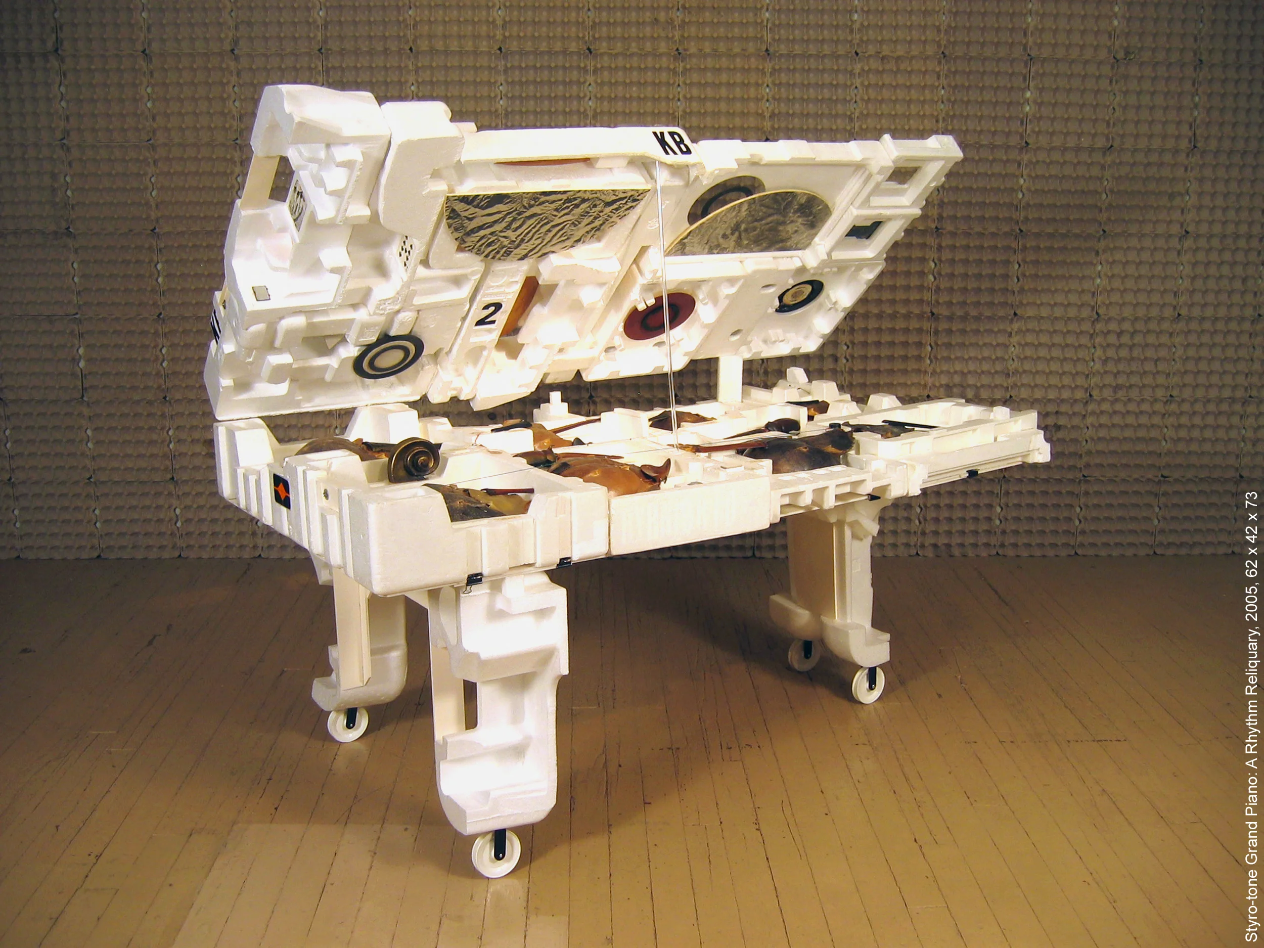 ‘Styro-tone Grand Piano: a Rhythm Reliquary’ , 2005, 62 x 42 x 73 (with top open). Made from street-found Styrofoam containers and other detritus, the sculpture plays with the idea of reliquaries (sacred objects) presented in a kind of natural history museum environment, referencing a cabinet of curiosities. Constructions of horseshoe shell crabs, insects, violin parts, and other found objects reflect the iconography of string instruments. The lightness of the material makes it very portable, and although playable as a percussion instrument (amplified with multiple transducers), it is predominantly a visual piece with only one string and no keyboard.