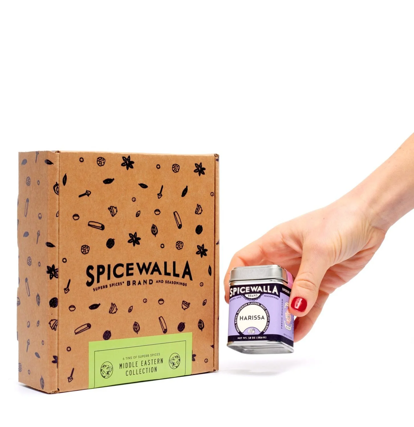 A hand sets a lavender spice tin beside a patterned kraft gift box.