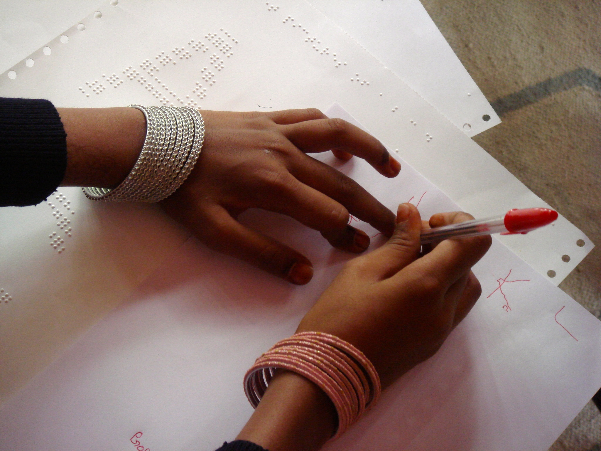Using one hand to hold the pen and the other to track where the horizontal line should be drawn, she successfully writes the letter