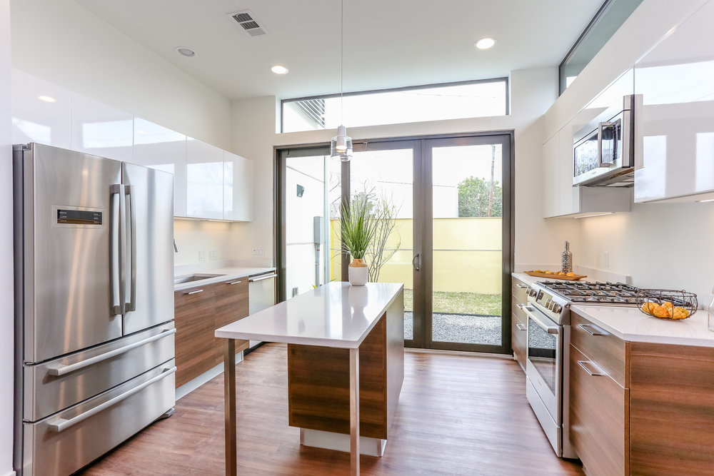  A beautifully appointed kitchen with sleek European style cabinetry, gleaming Silestone countertops, and stainless steel appliances opens onto an adjacent garden. 