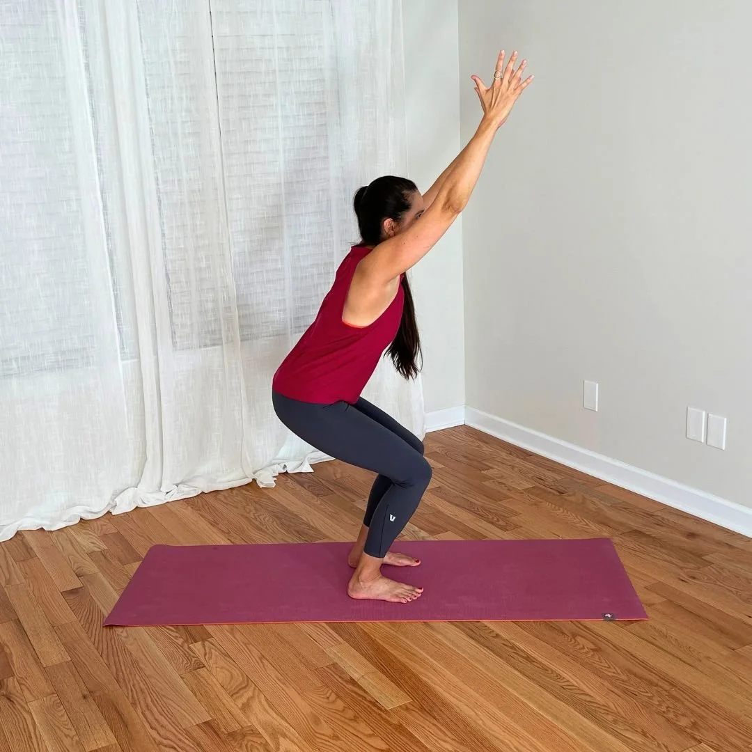Yoga teacher practicing chair pose with arms reaching overhead