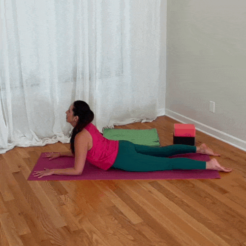 Jenni demonstrates sphinx cat/cow, alternating between thoracic extension and flexion while supported on her forearms.