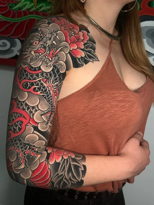 Japanese dragon and peony full sleeve tattoo in black and grey with red accents by Daniele Tonelli.
