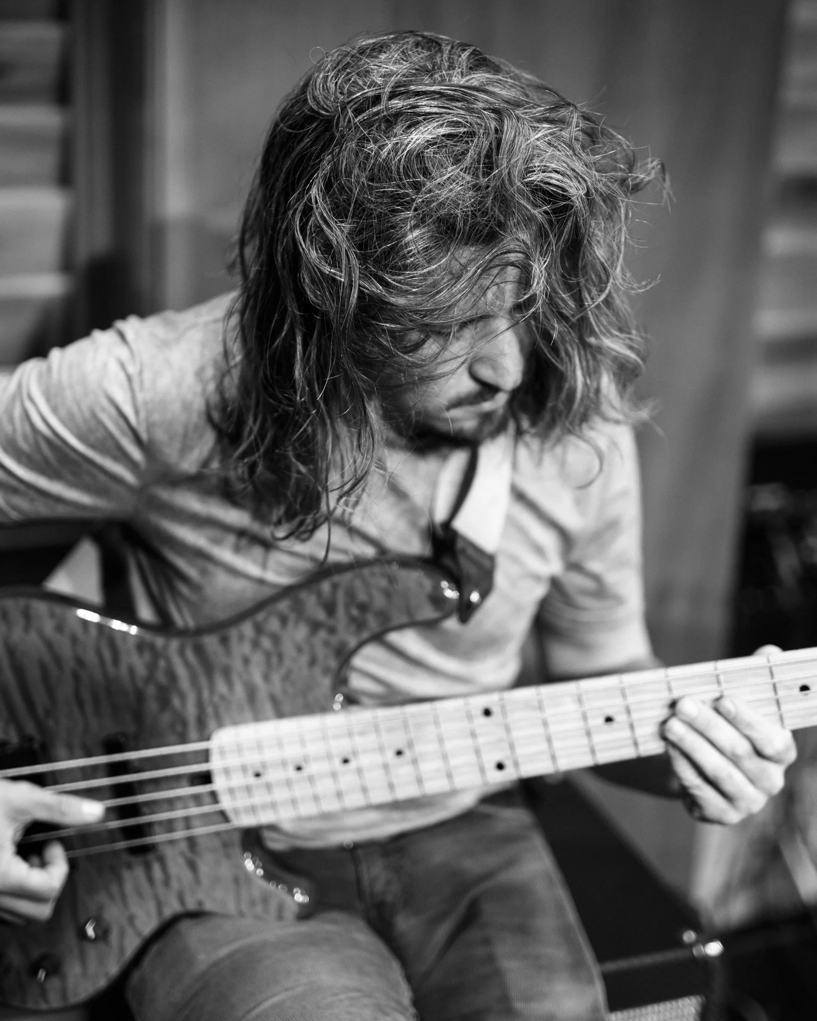 Black and white photo of a man with long wavy hair playing an electric guitar.
