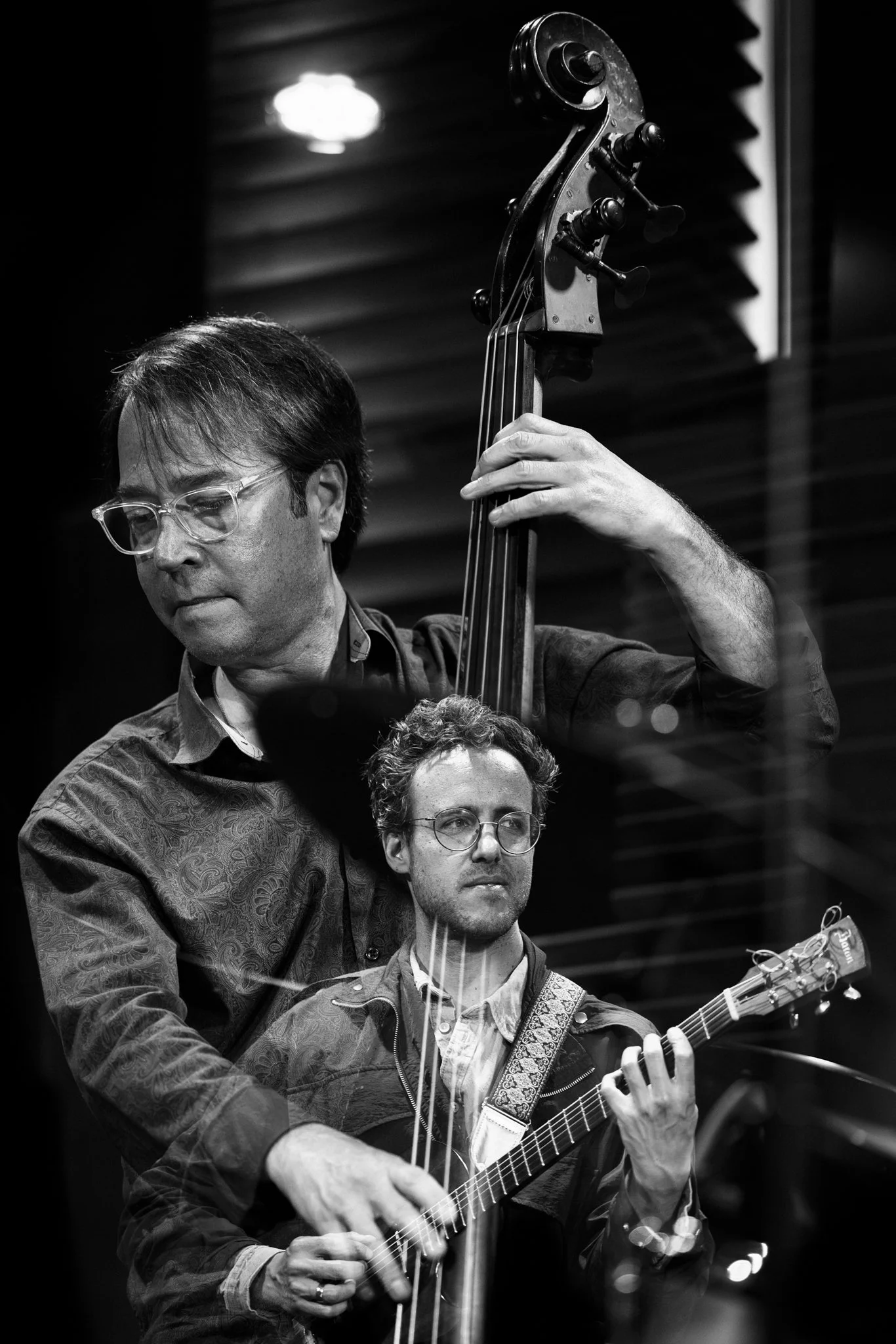 Two musicians performing with a double bass and an acoustic guitar in a recording studio.