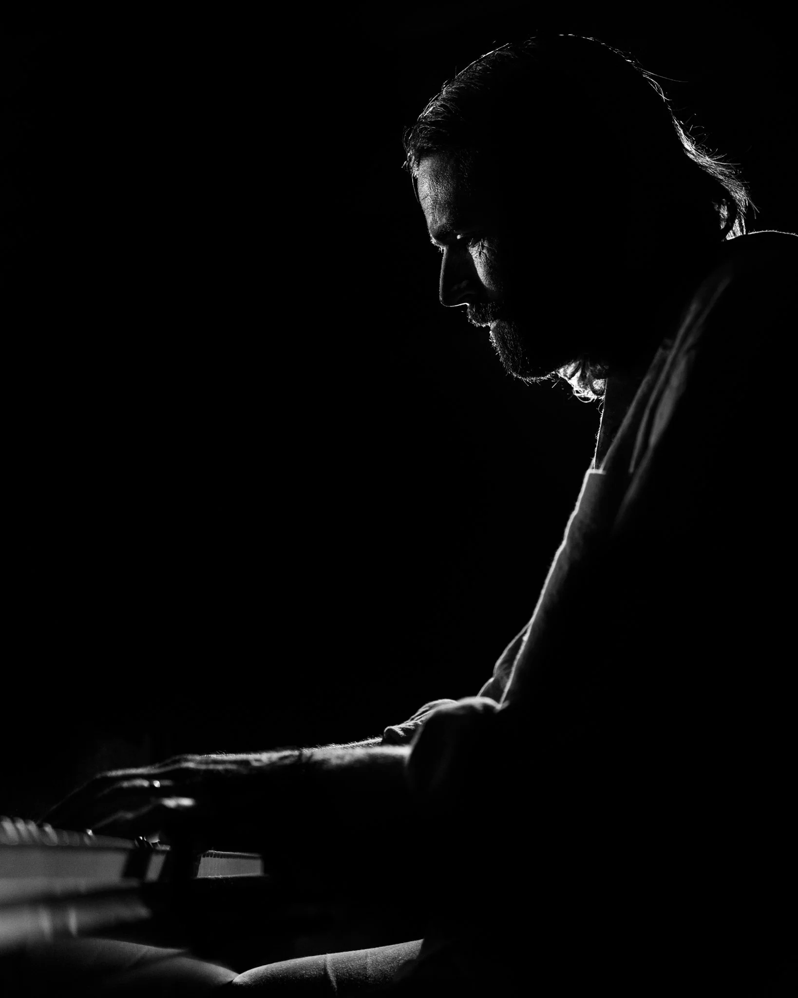 Silhouette of a man playing piano in low light