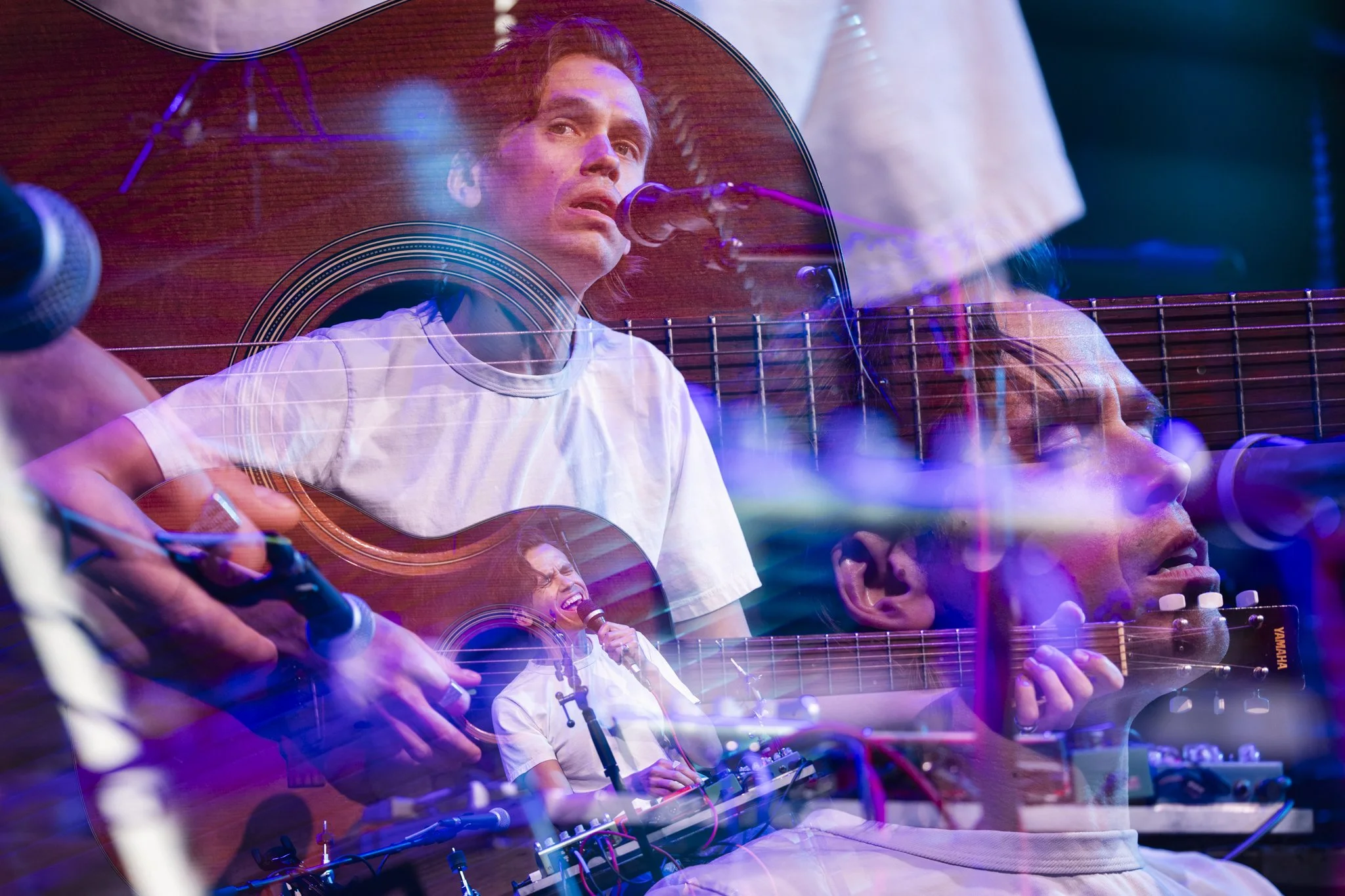 A musician performs on stage with multiple overlayed images of himself singing, playing guitar, and using audio equipment, amidst colorful stage lighting.