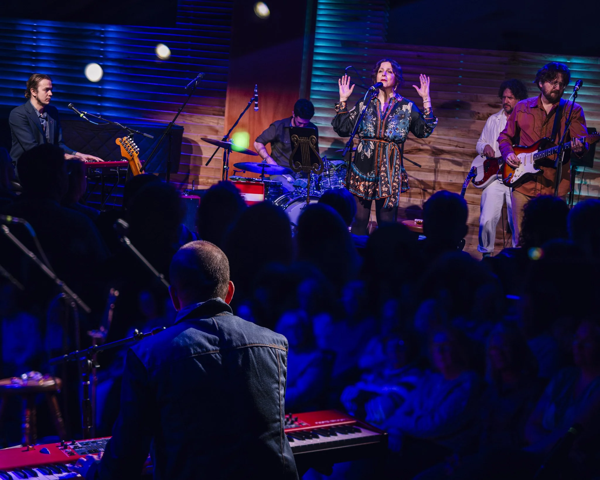 Band performing live on stage with audience watching.