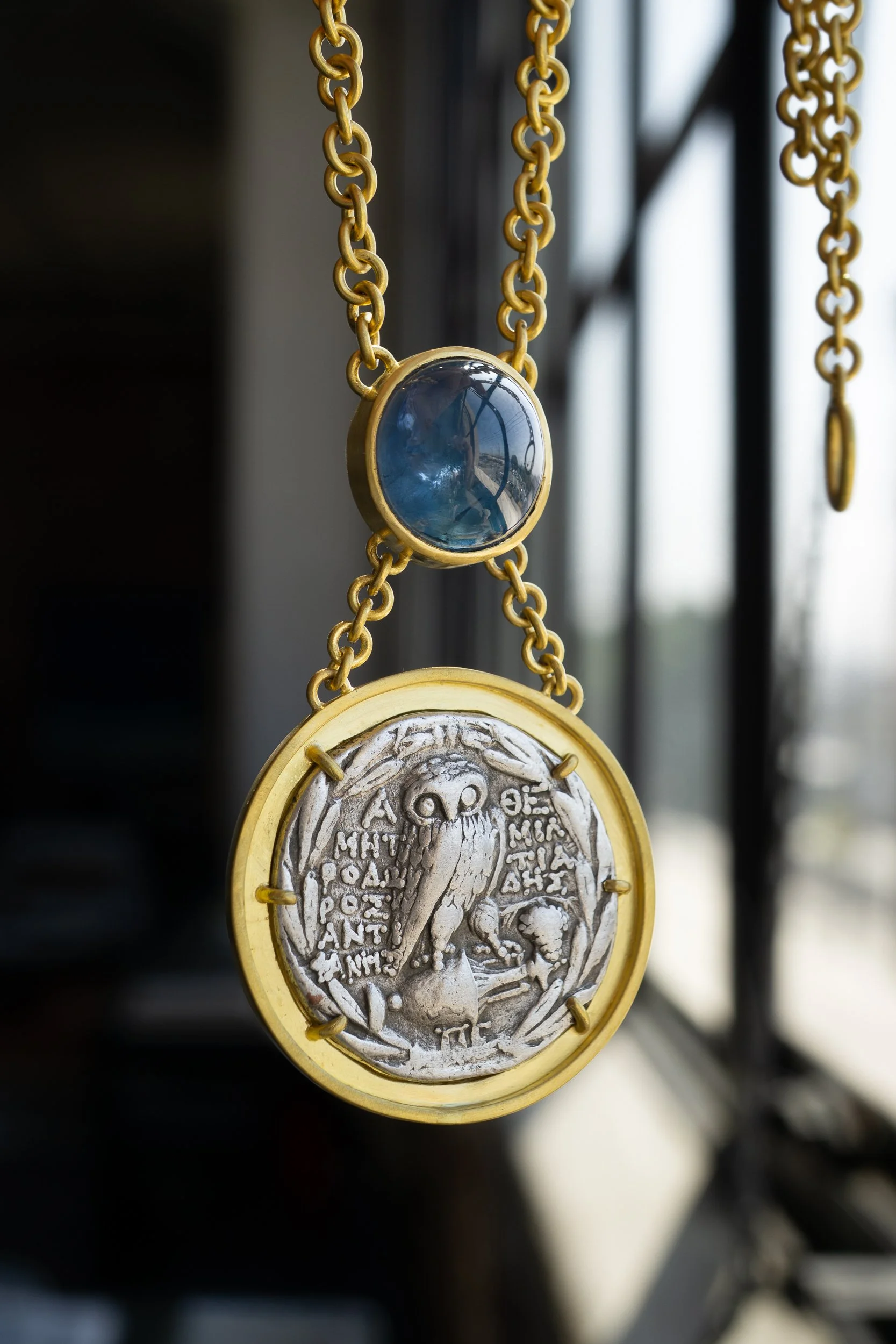 Aegean Necklace, suspended in window showing detail of owl coin and sapphire.