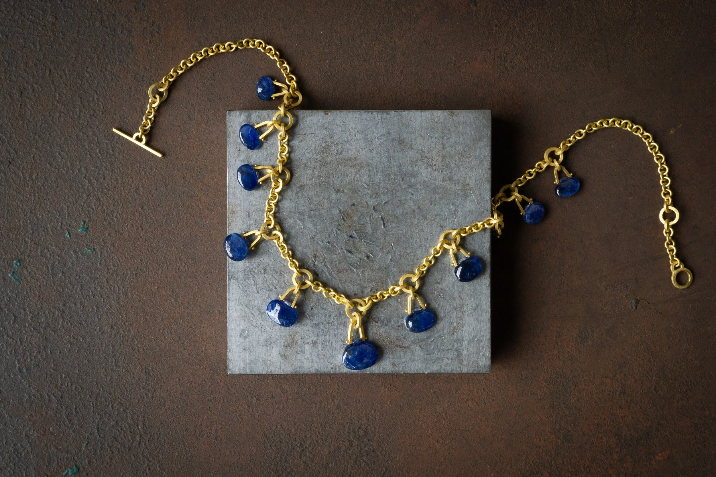 Tabiz Necklace in 22k gold with antique Tabiz-cut sapphires on studio table.