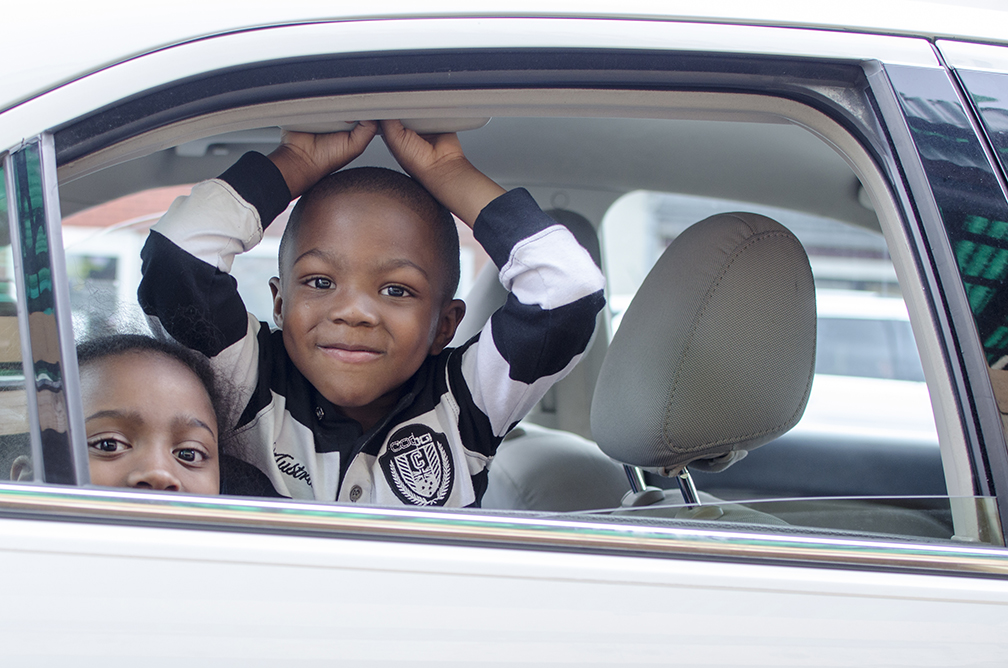 Two children wait in the car as their parents go grocery shopping at an outdoor fresh food shop in downtown Pittsburgh, PA.