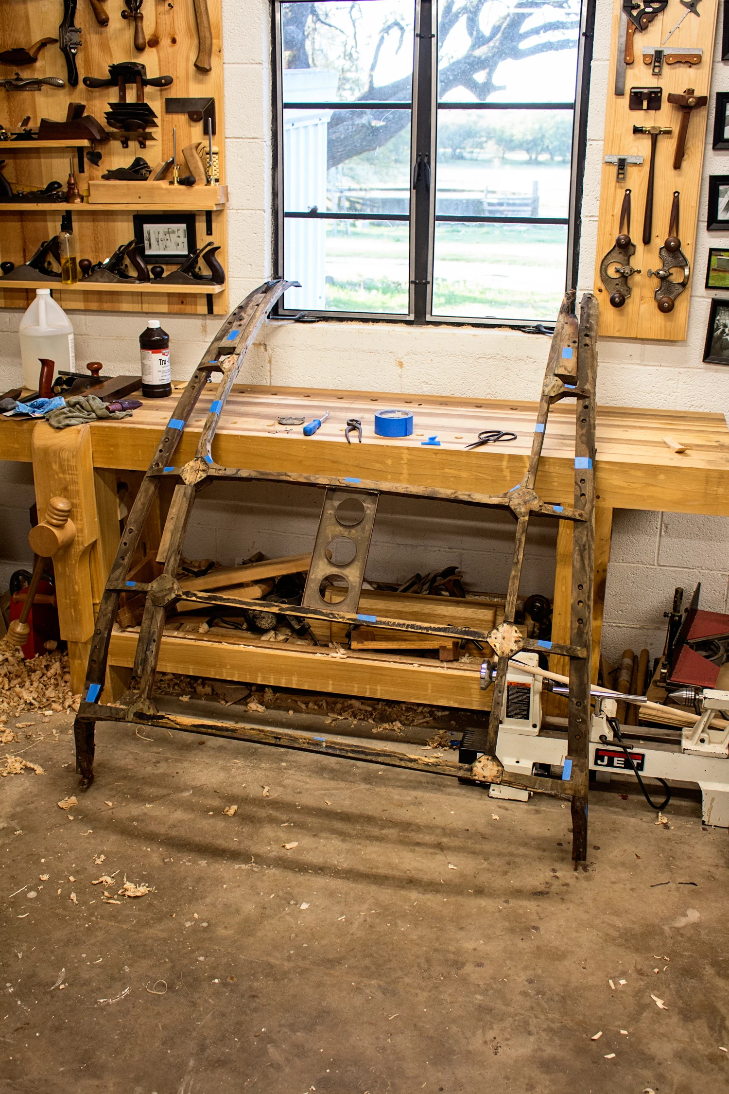  We are now addressing issues with the rear body support frame. The four main runners (for lack of a better term) are completely rotten at the rear, which is where they are exposed to moisture from the wheel wells. The runners are all bent laminated construction, using Ash like the rest of the wooden components. These four runners provide all of the strength in this structure. Because of this, they will be getting replaced. The connecting pieces in between can all be reused. The first step in all of this is to label each individual component. Some blue painter's tape and a permanent marker work well for me. After everything is labeled, the detailed work begins. Each joint must be thoroughly documented with measurements, photographs, and notes on each section. I don't have another XK120 handy for comparison, my notes and my photos are all I'll have. This is probably the most important step of this entire rebuild process. Once I'm happy with my documentation, I'll begin taking this apart, assessing the condition of each individual piece. Most will just need the old glue scraped off, a few might need some checks and cracks fixed