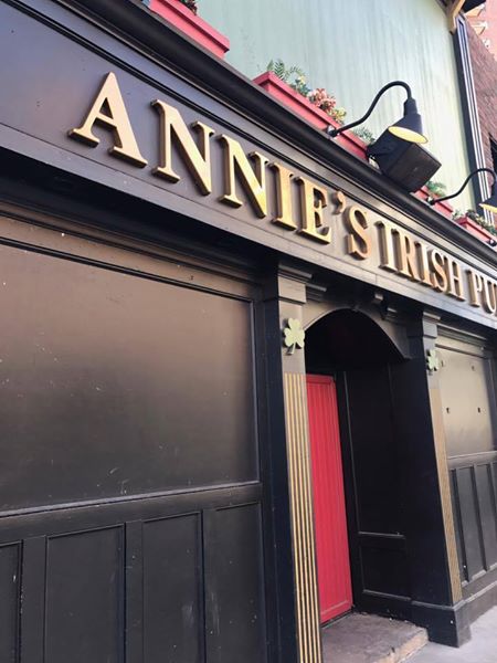 Front entrance detail of Annie’s Irish Pub in Des Moines, Iowa, highlighting the signature red door and Irish pub charm
