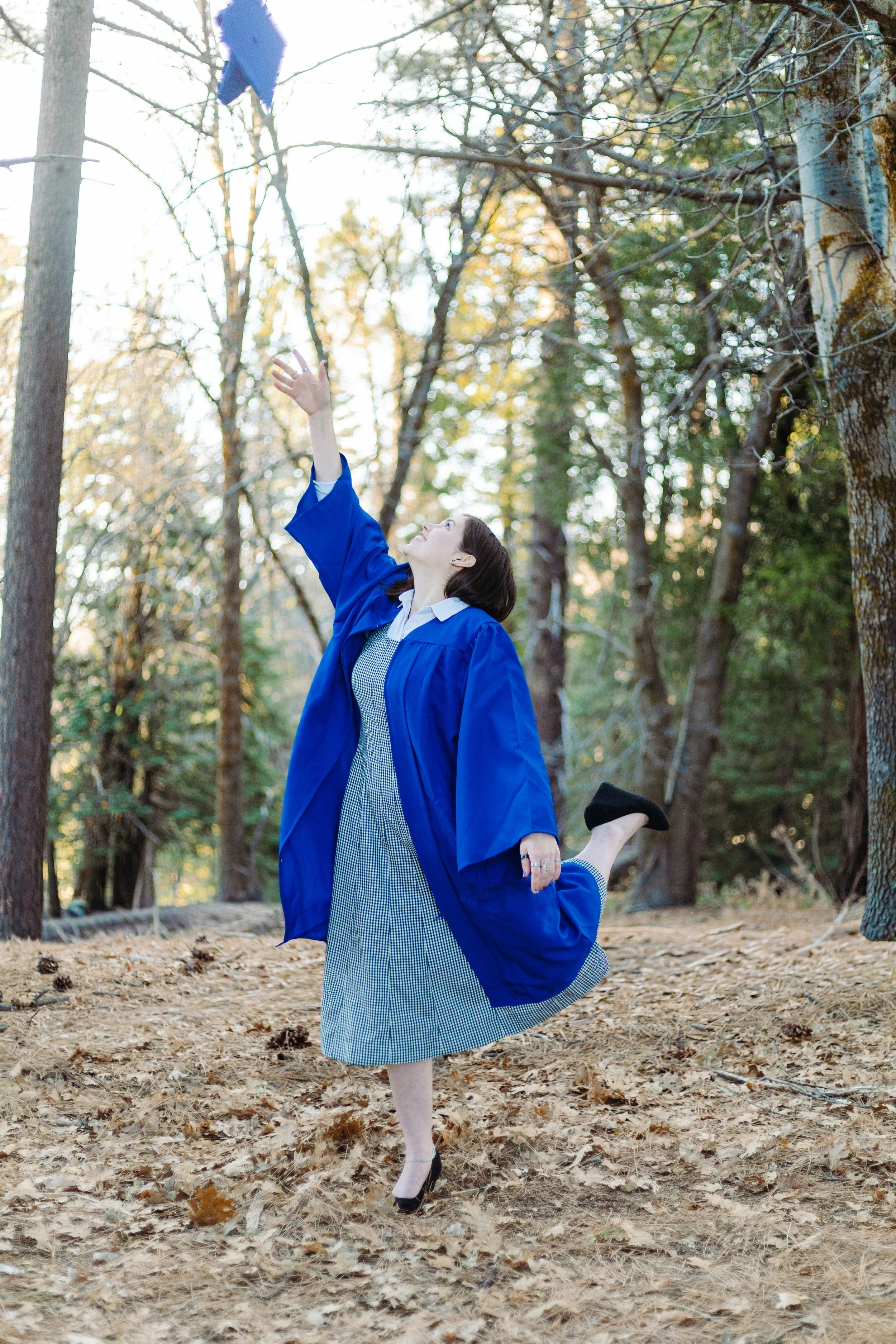 Excited high school graduate tossing her graduation cap into the air in celebration during senior photos.