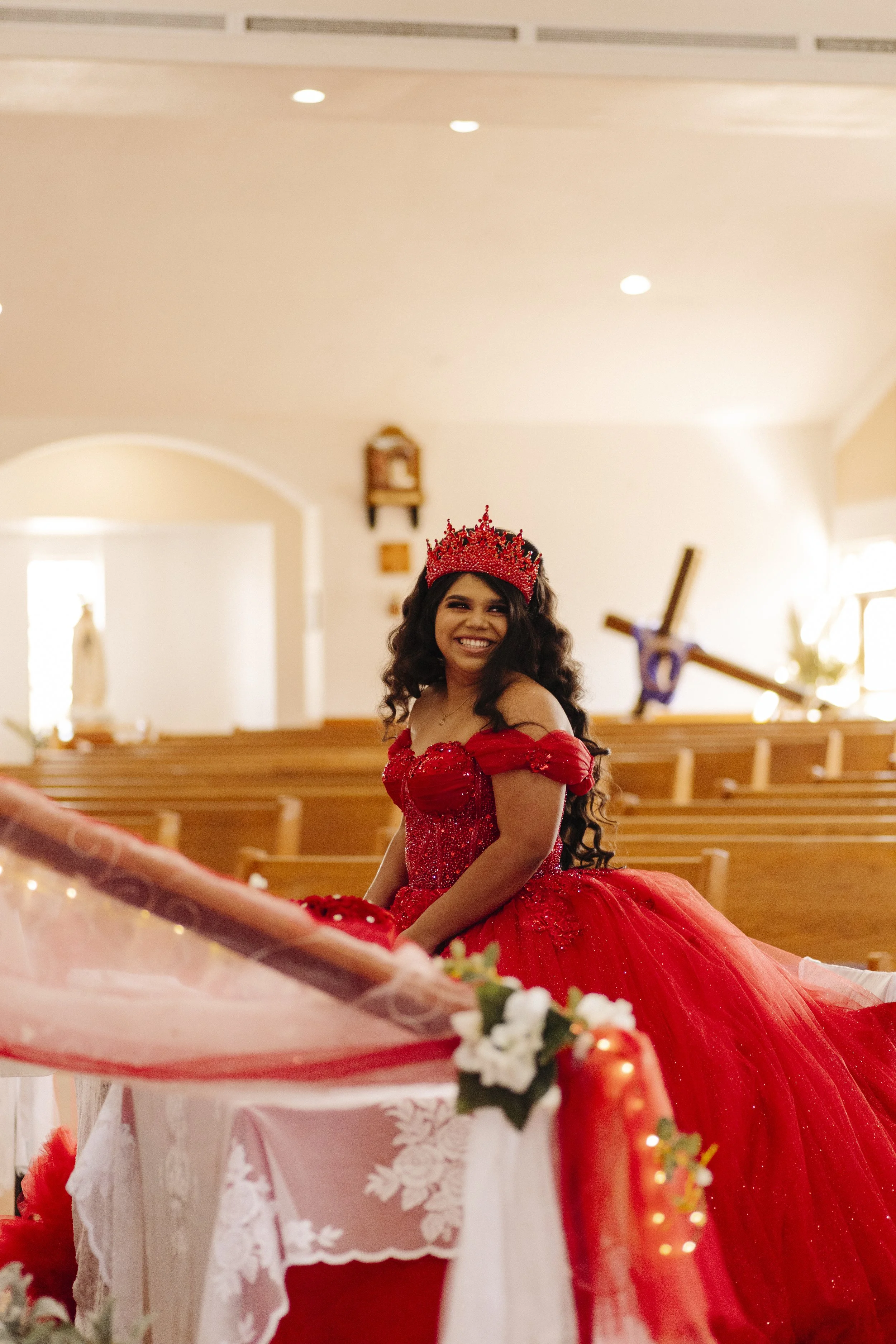 Quinceañera smiling inside a church in her elegant dress
