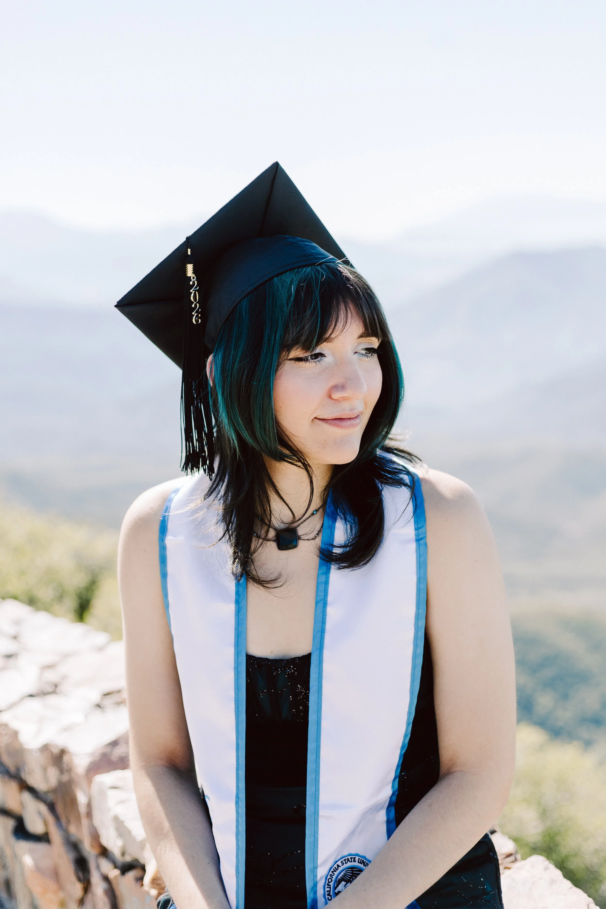 California State University San Bernardino graduate sitting outdoors in graduation attire