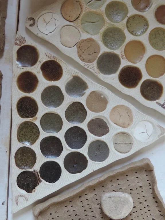 Triaxial blend tests fired to 2250 f. in oxidation. Lower left tile shows promising results for a diverse range of glazes using slate powder, refractory kaolin, and silty clay soil collected in a marble quarry