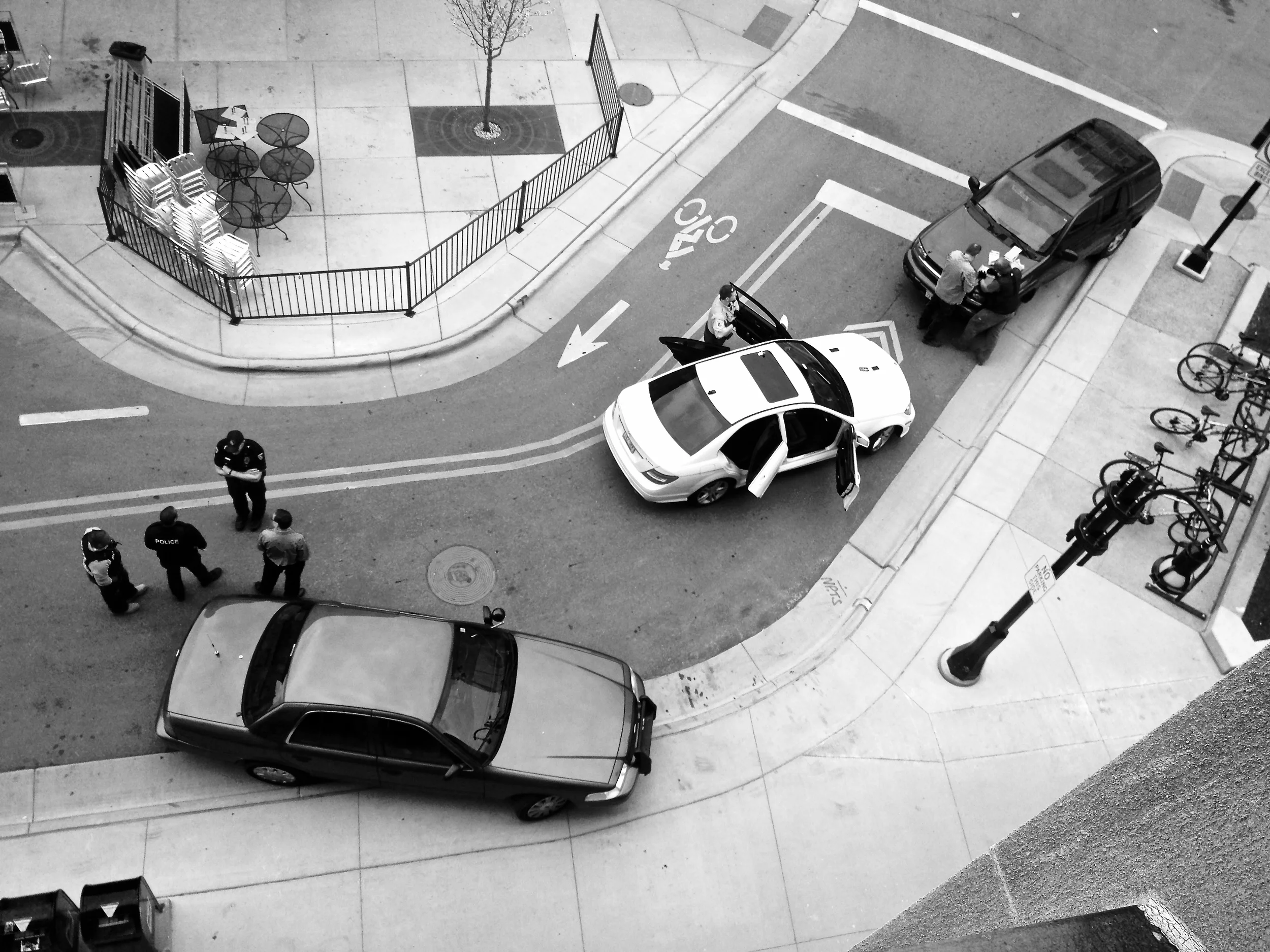 Scene of the Crime (2). Downtown. Madison, Wisconsin. April 2016. Police talk and gather evidence at the scene of an armed traffic stop and arrest. © William D. Walker