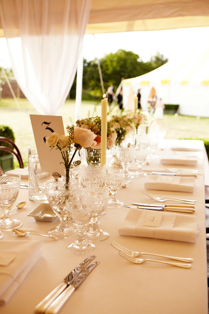 Cut crystal glasses and creamy garden roses adorn the white-on-white table settings.