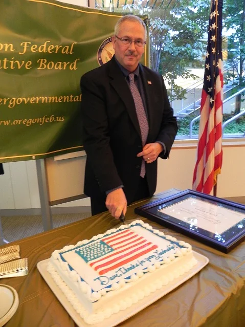 David Ferguson, departing 2017 Chair of the Oregon Federal Executive Board of Directors, cutting the "thank you, dave" cake following the swearing in of the 2018 chair, Jeninifer baker (SBA). Vice Chair, tina burke (tsa) was not present.