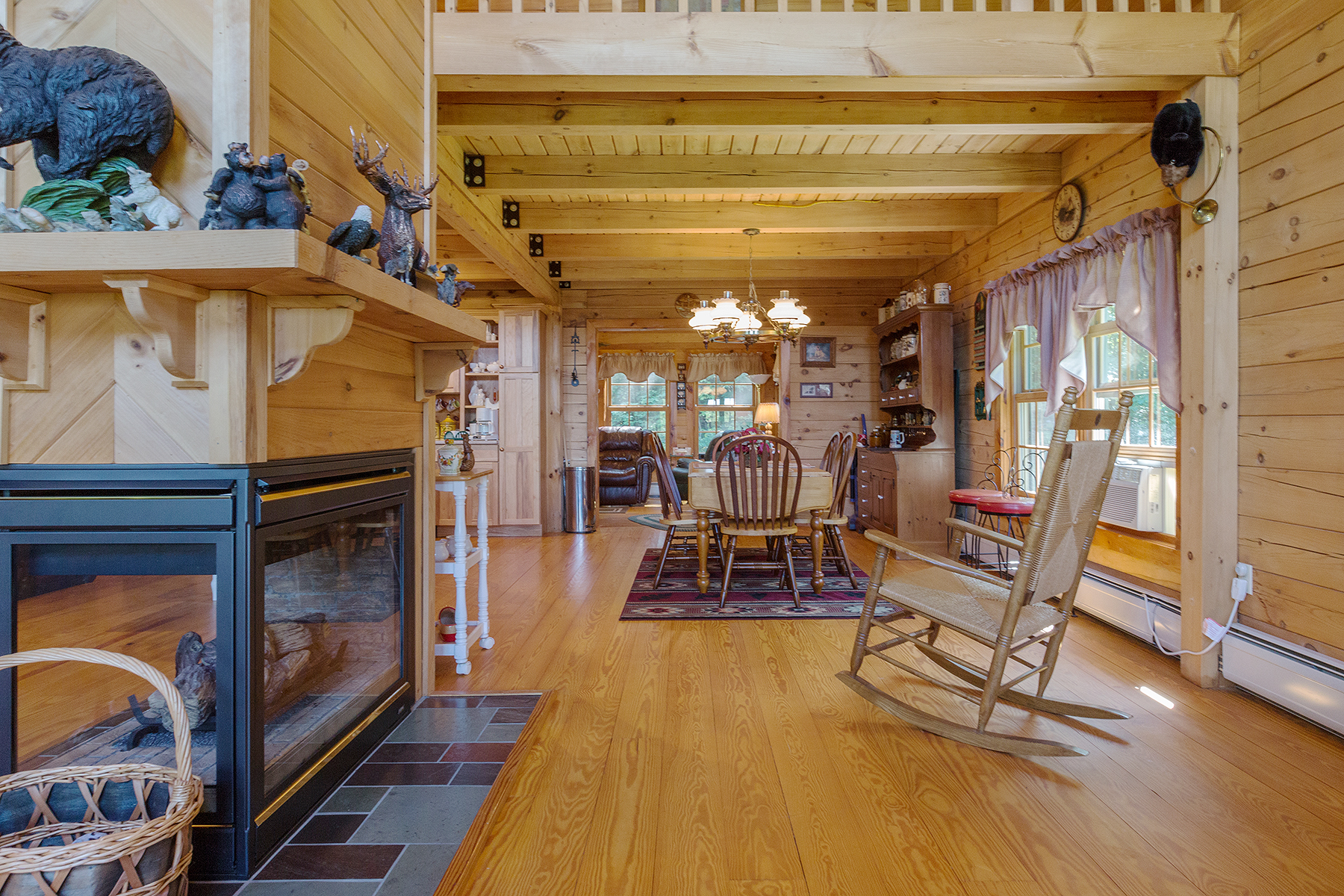  Open concept showing wrap around fireplace looking down straight onto the dining room.  Pine colored logs and light colored hard wood floors. 