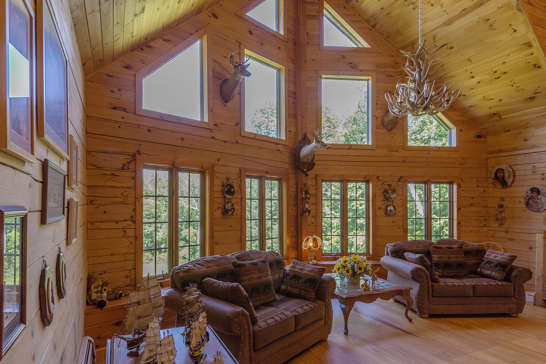  Side view of inside of the living room.  Wall to the left has pictures hanging and the main wall of the house has tied window pattern.  The bottom tier has 8 side by side windows, above that are 4 additional single windows and above that are two sma