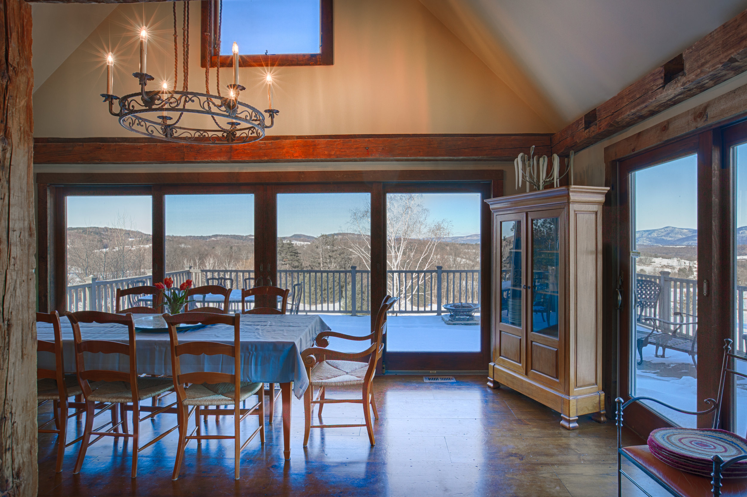  Wide open view looking into dining room. Dining room walls are lined with floor to ceiling windows that overlook a deck with a Mountain View.  There is a table in the center of the dining room with multiple chairs and an armour tucked in the corner 