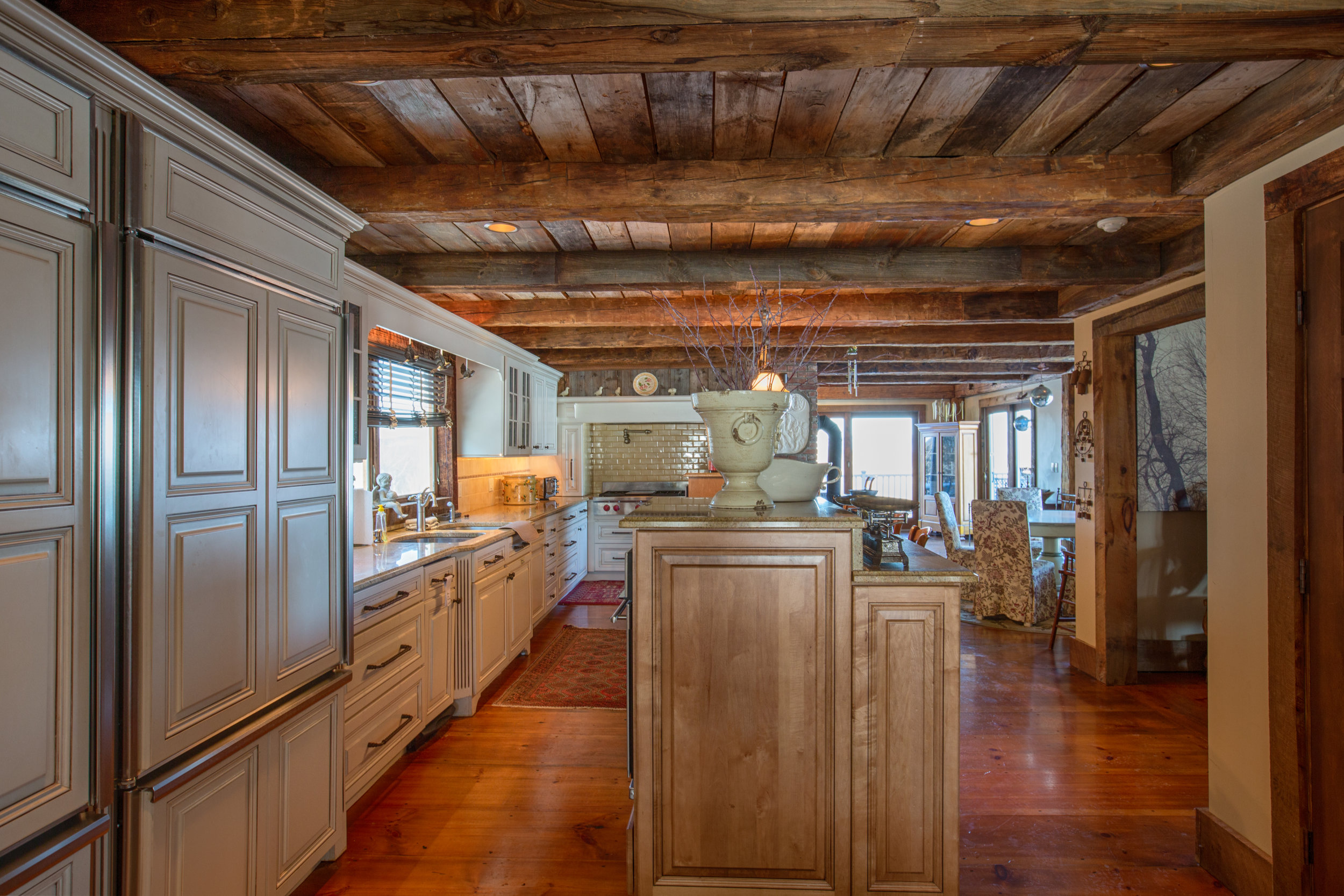  View from side of kitchen showing the over lay refrigerator.  Exposed wood beam ceilings.   