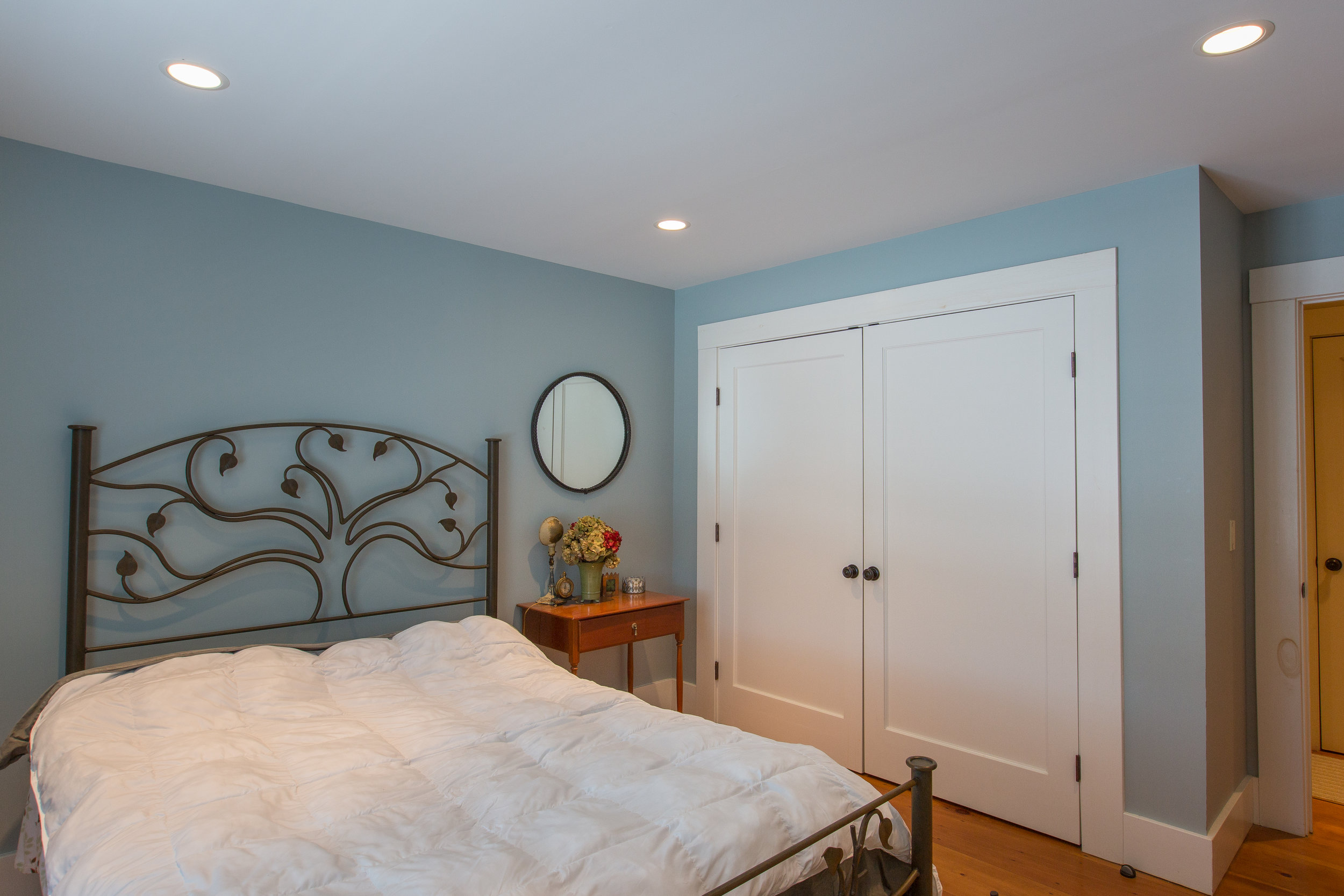  Another bedroom with bed in the center of the room and white double closet doors. Recess lighting and hardwood floors are a few features in this room 