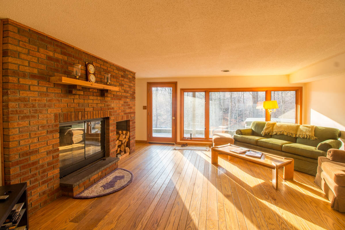  Living area with brick encased fireplace.  Large windows on the back wall and very nice skinny plank hardwood floors.  