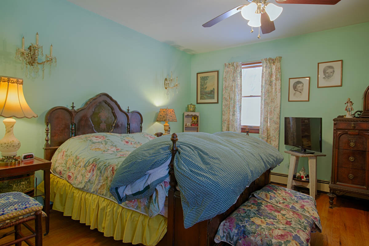  Bedroom with a big bed in center of the wall.  One window is visible in the photo.   