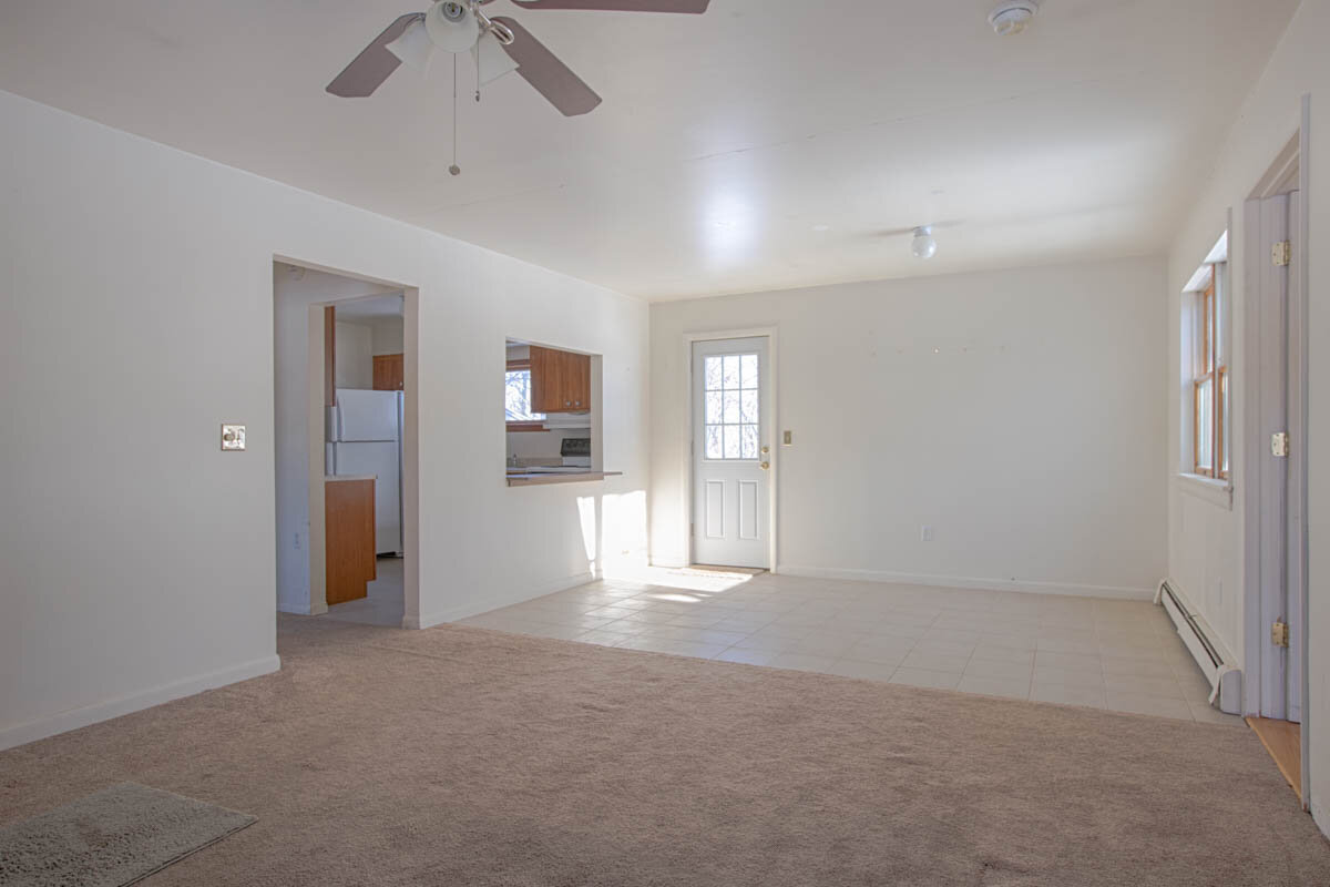  Inside looking from living room to entry way.  Entry way is tile floor and living room is carpeted.  Kitchen is to the left of the photo and you can also see a ceiling fan in the living room. 