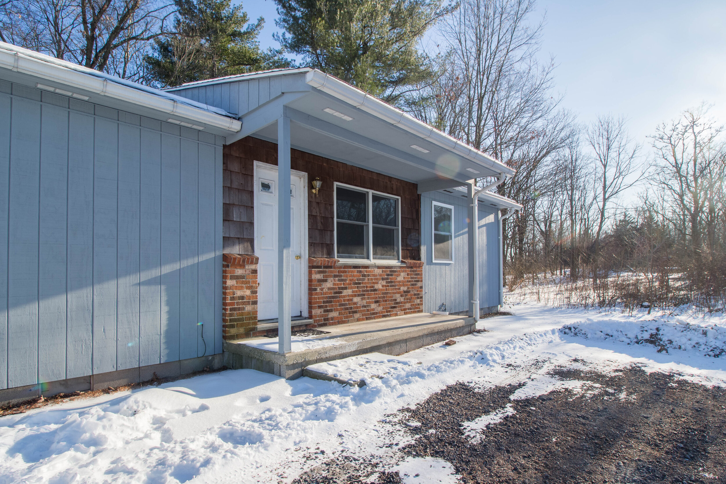  Outside of ranch style home with a brick front and a small covered porch. 