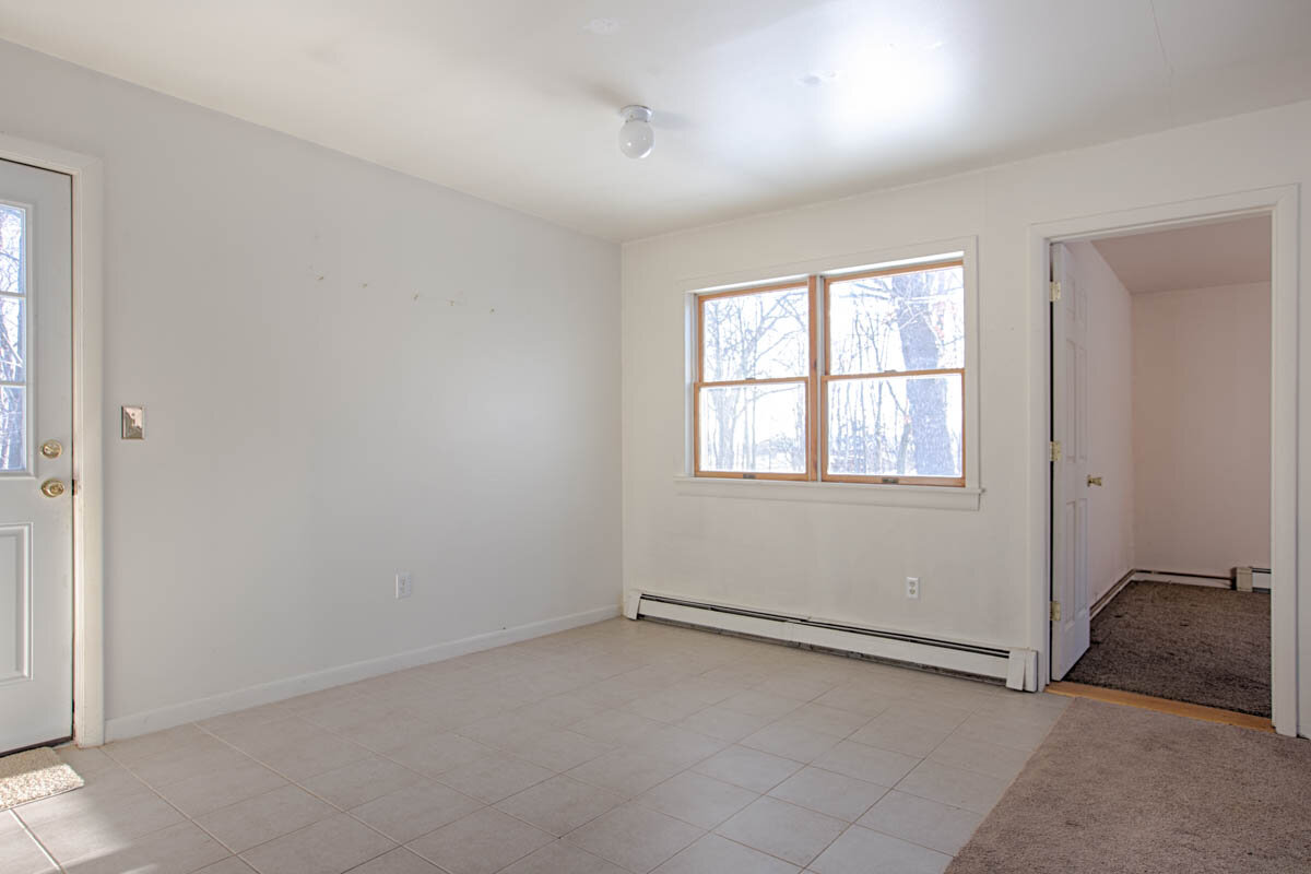  Corner of entry way showing tile floor, double window and a floor opening to a bedroom. 